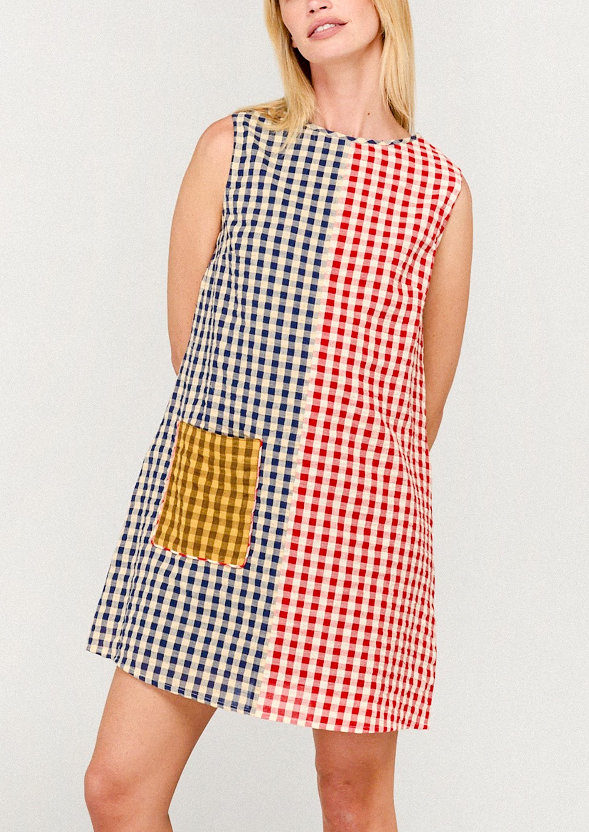 Woman wearing a patchwork dress with red, white, and blue checkered pattern on a plain background