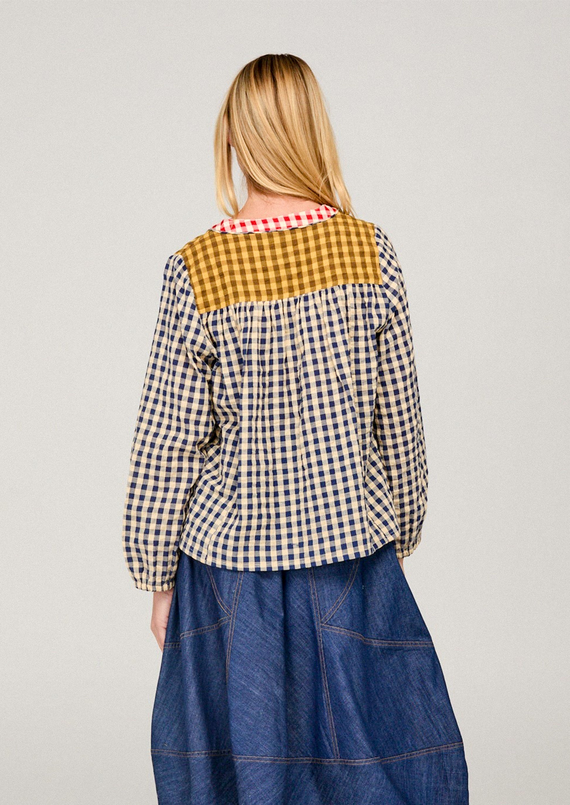 Person wearing a colorful checkered shirt with a plain background