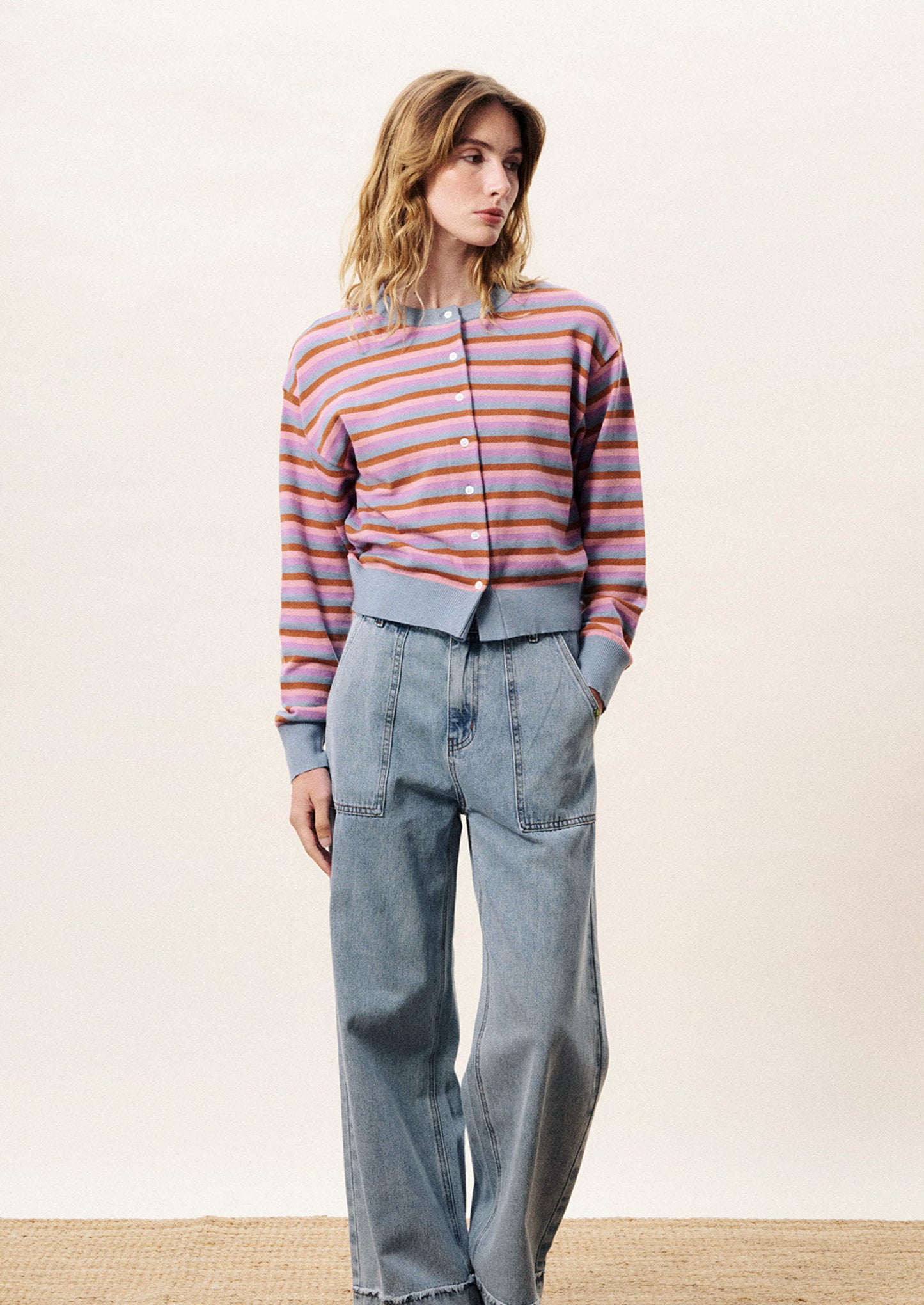 Woman wearing a striped sweater and jeans on a plain background