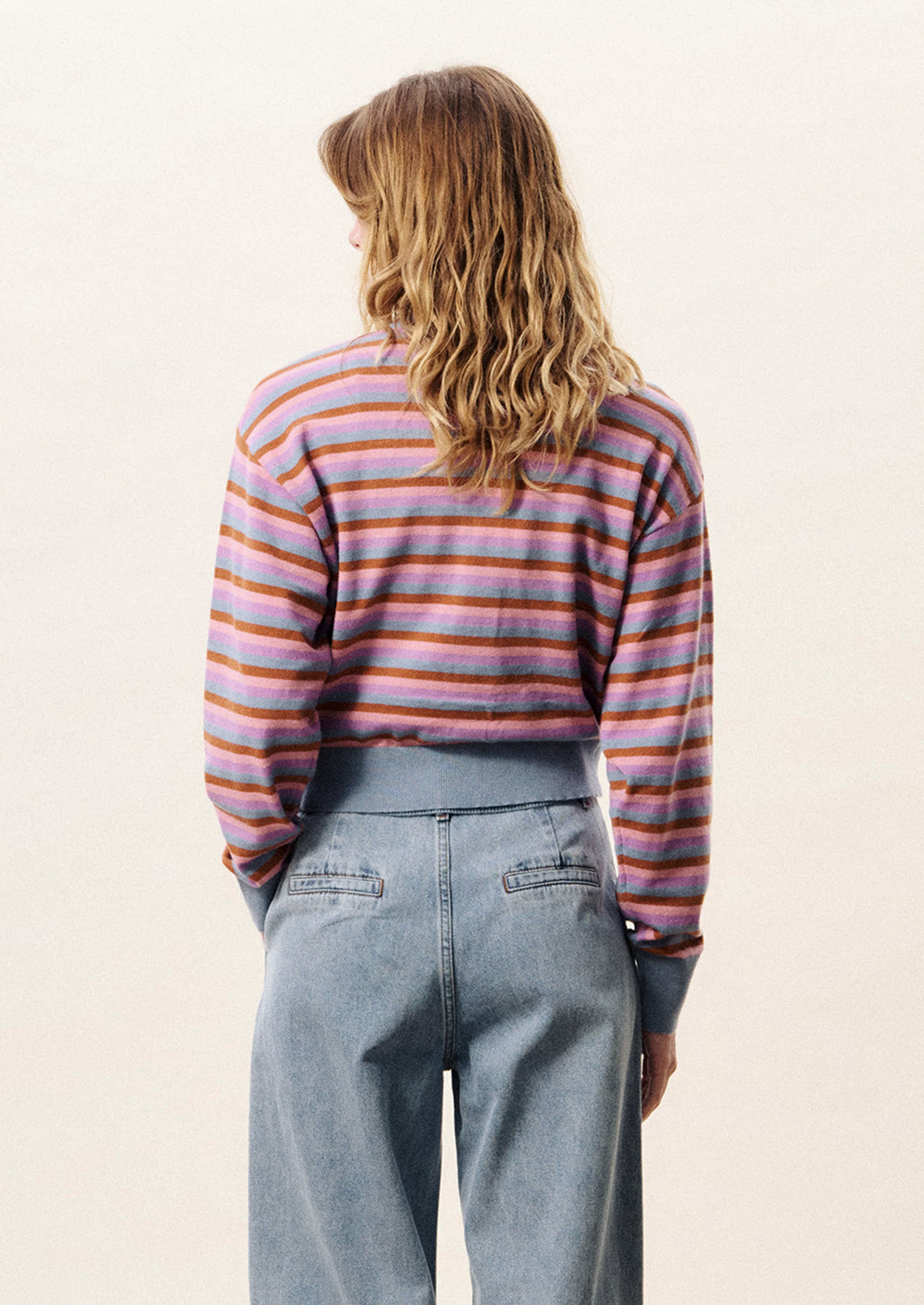 Person wearing a striped long-sleeve shirt and jeans on a plain background