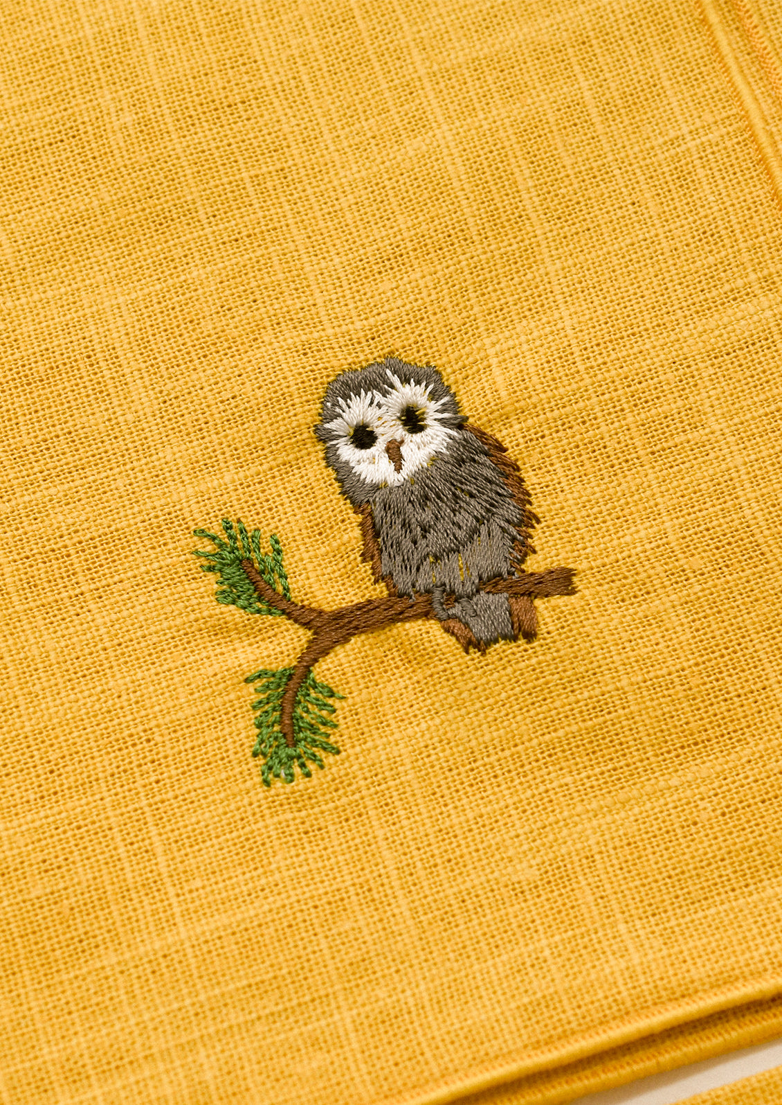 Embroidered owl on a yellow fabric background