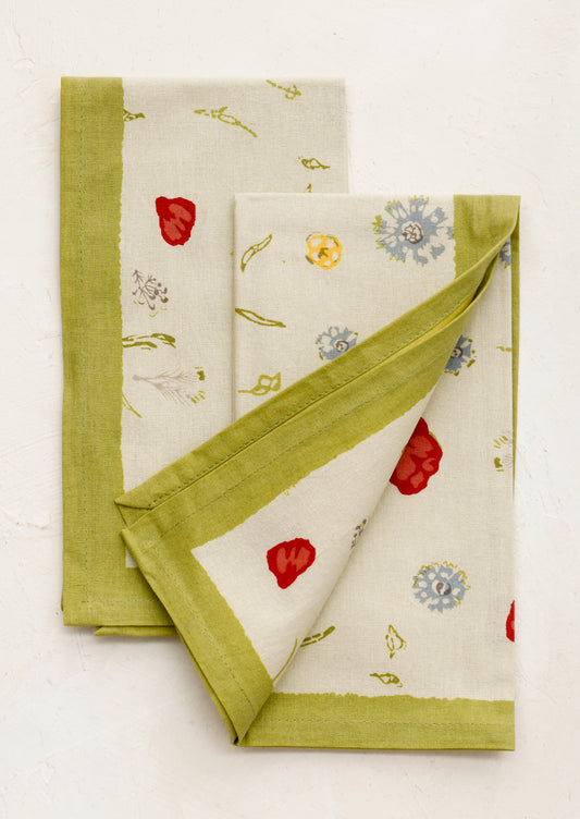 Two floral-patterned cloths with green borders on a white background