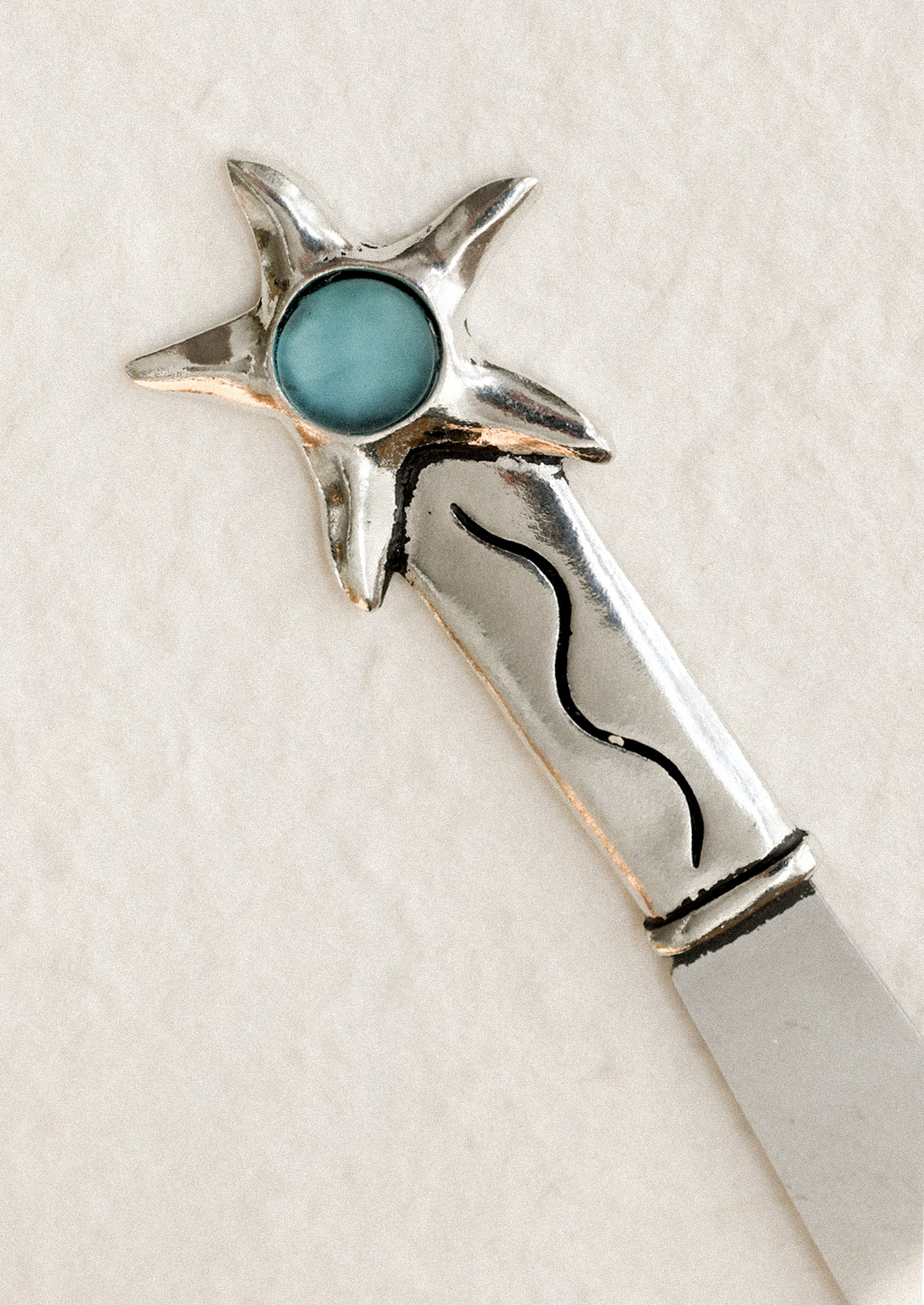 Silver butter knife with turquoise stone on a white background
