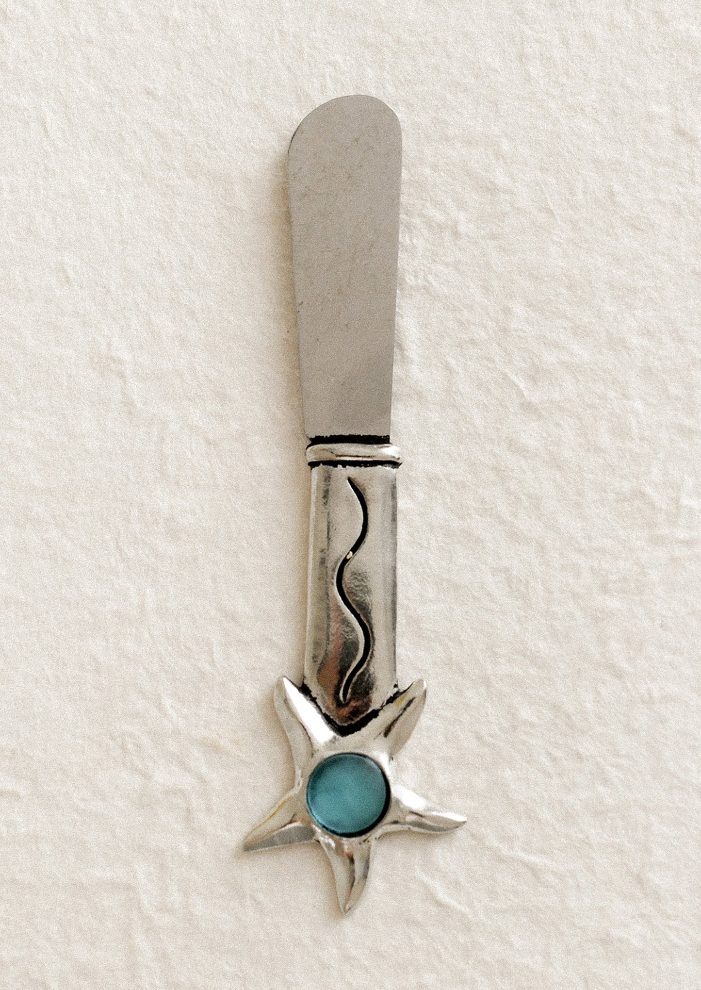 Silver butter knife with turquoise stone on a white background