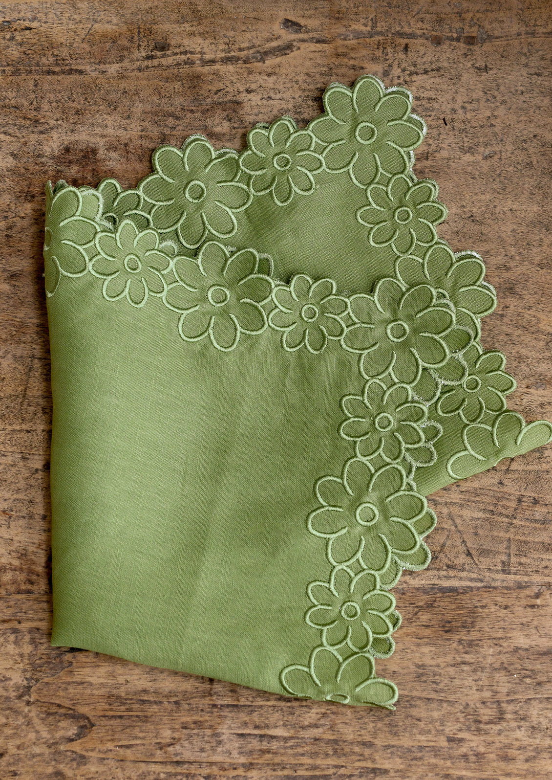 Green napkin with floral lace trim on a wooden surface