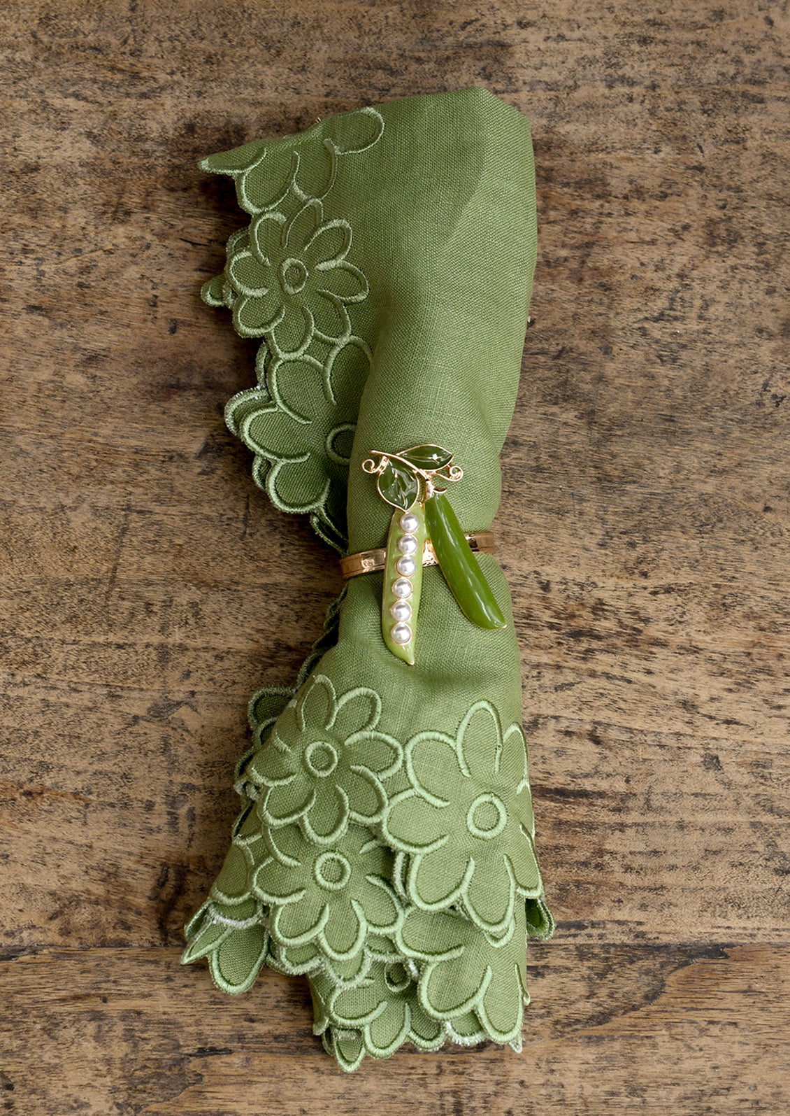 Green napkin with decorative ring on a wooden surface
