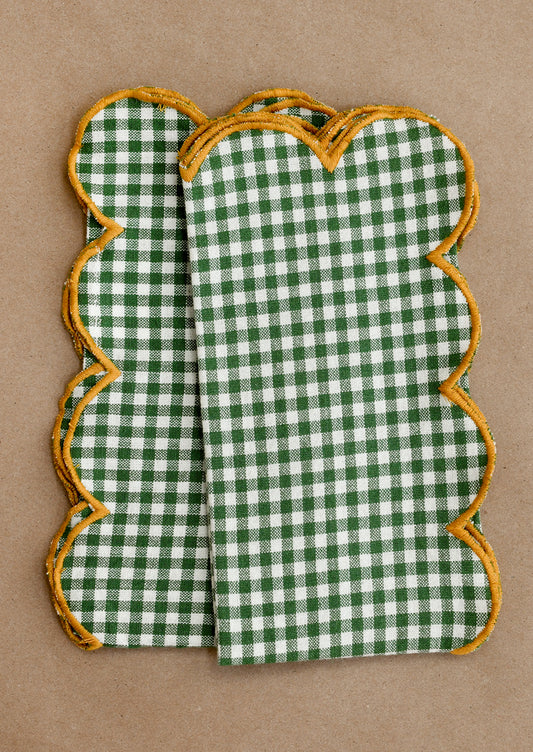 Green and white checkered cloth napkins with scalloped edges on a brown background