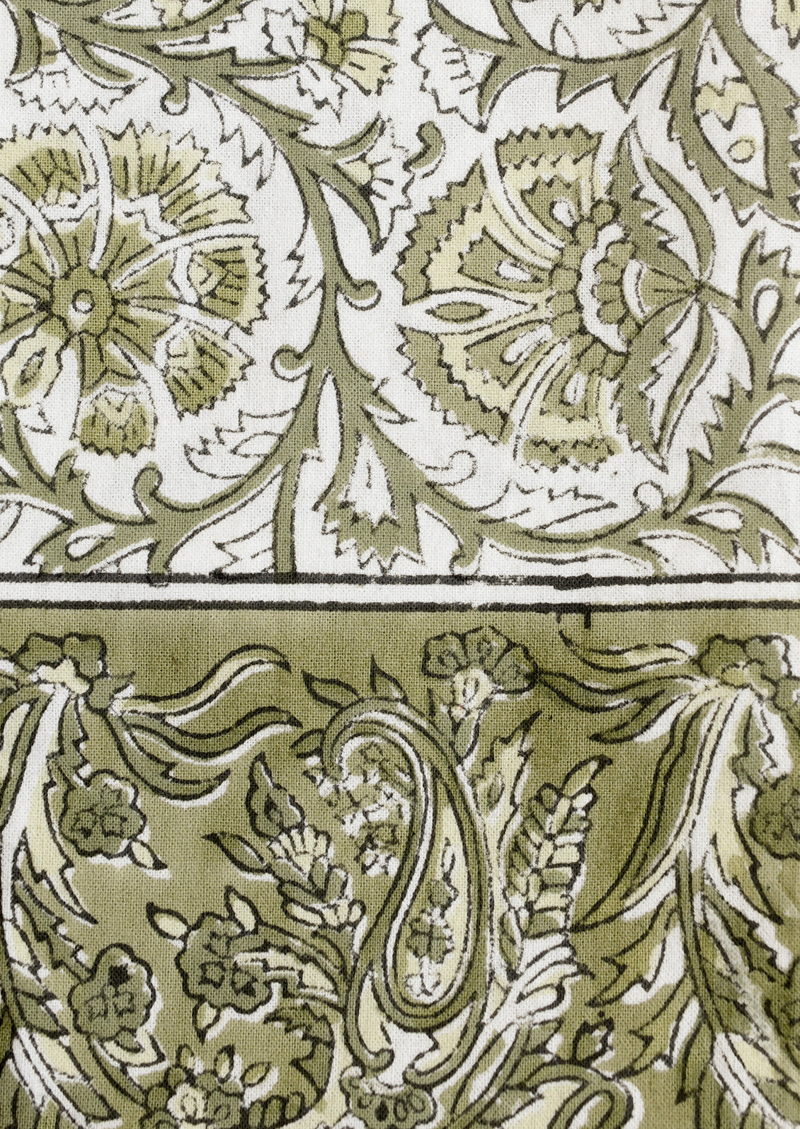 A set of cloth napkins in green and white traditional floral block print pattern.