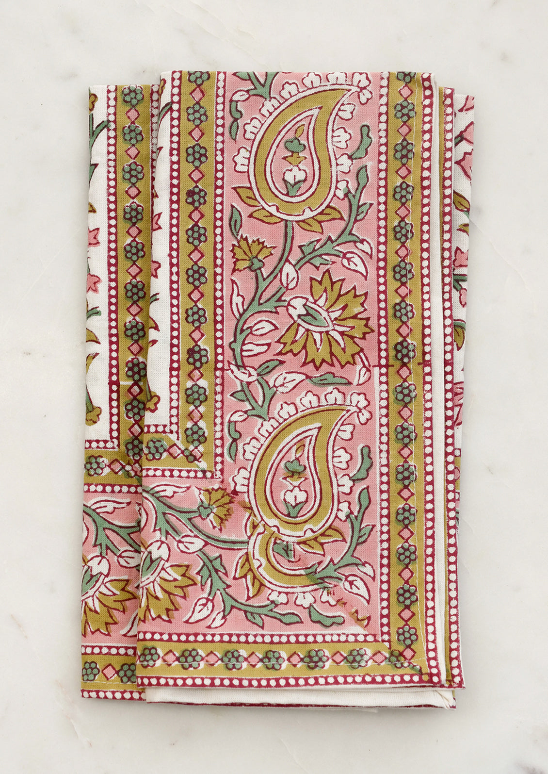 A set of cloth napkins in pink and mustard paisley print.