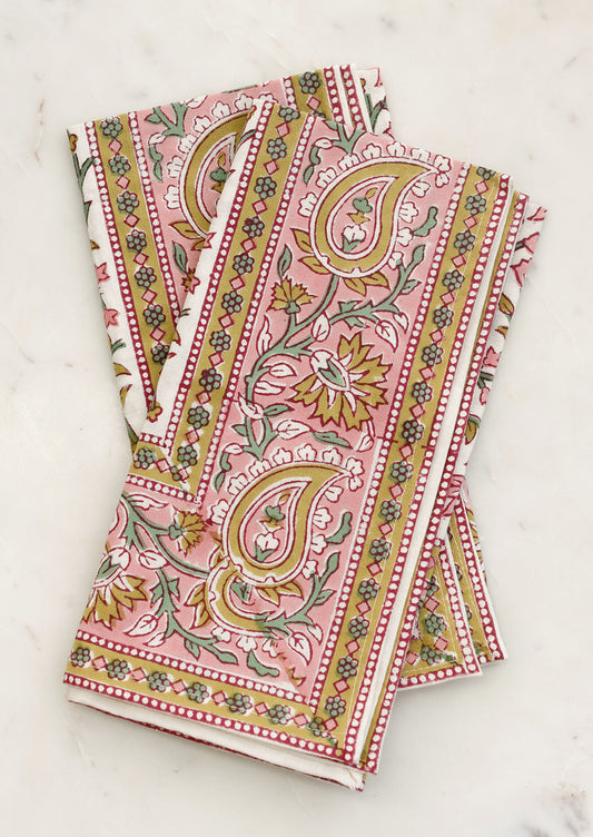 A set of cloth napkins in pink and mustard paisley print.