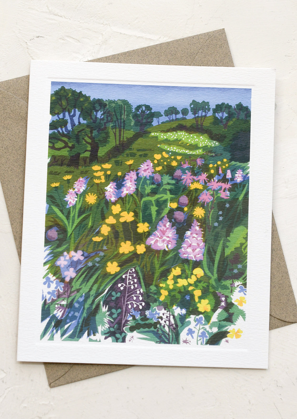 Greeting card with a colorful illustration of a field of flowers and trees on a white background.