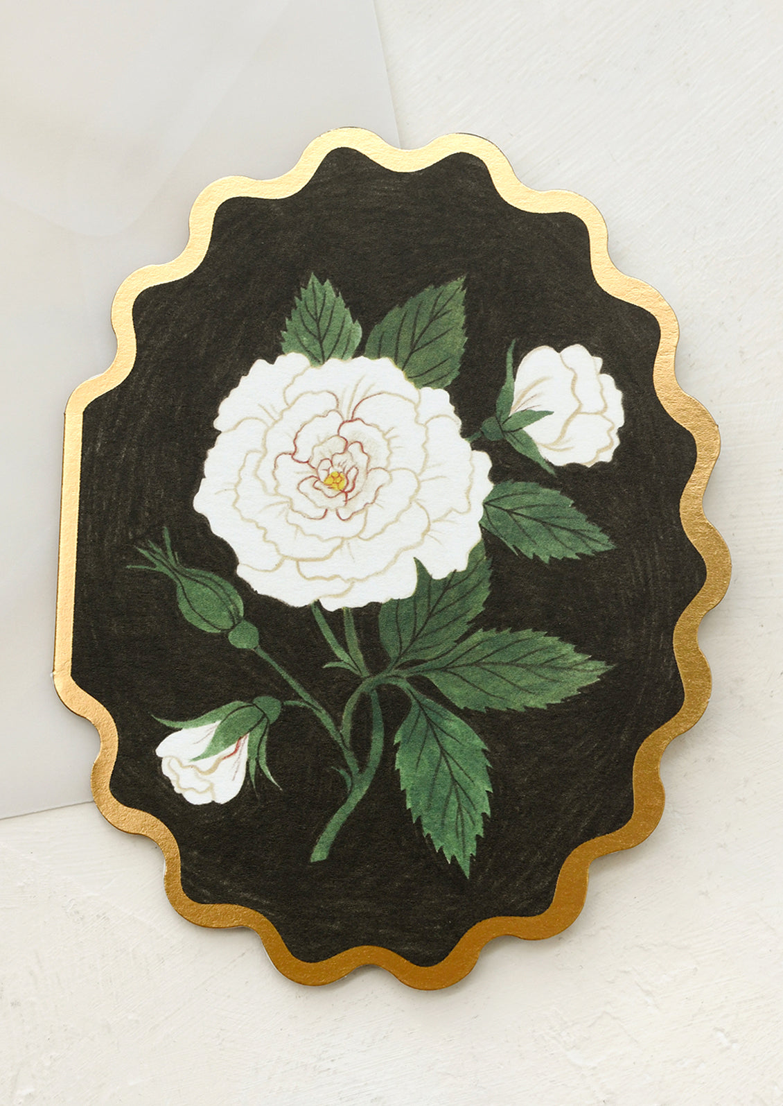 A scalloped diecut card with white rose on black background.