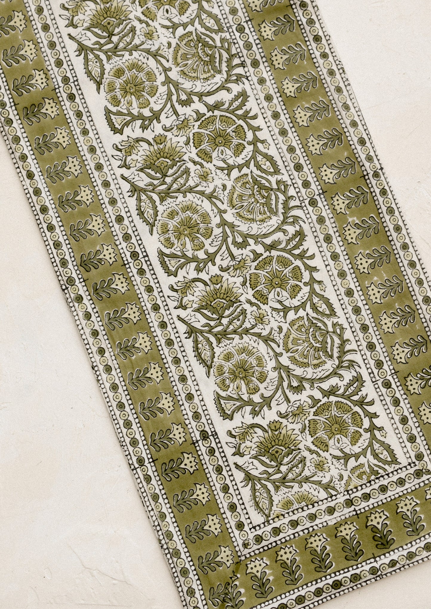 Decorative fabric with intricate green and white floral pattern on a beige background