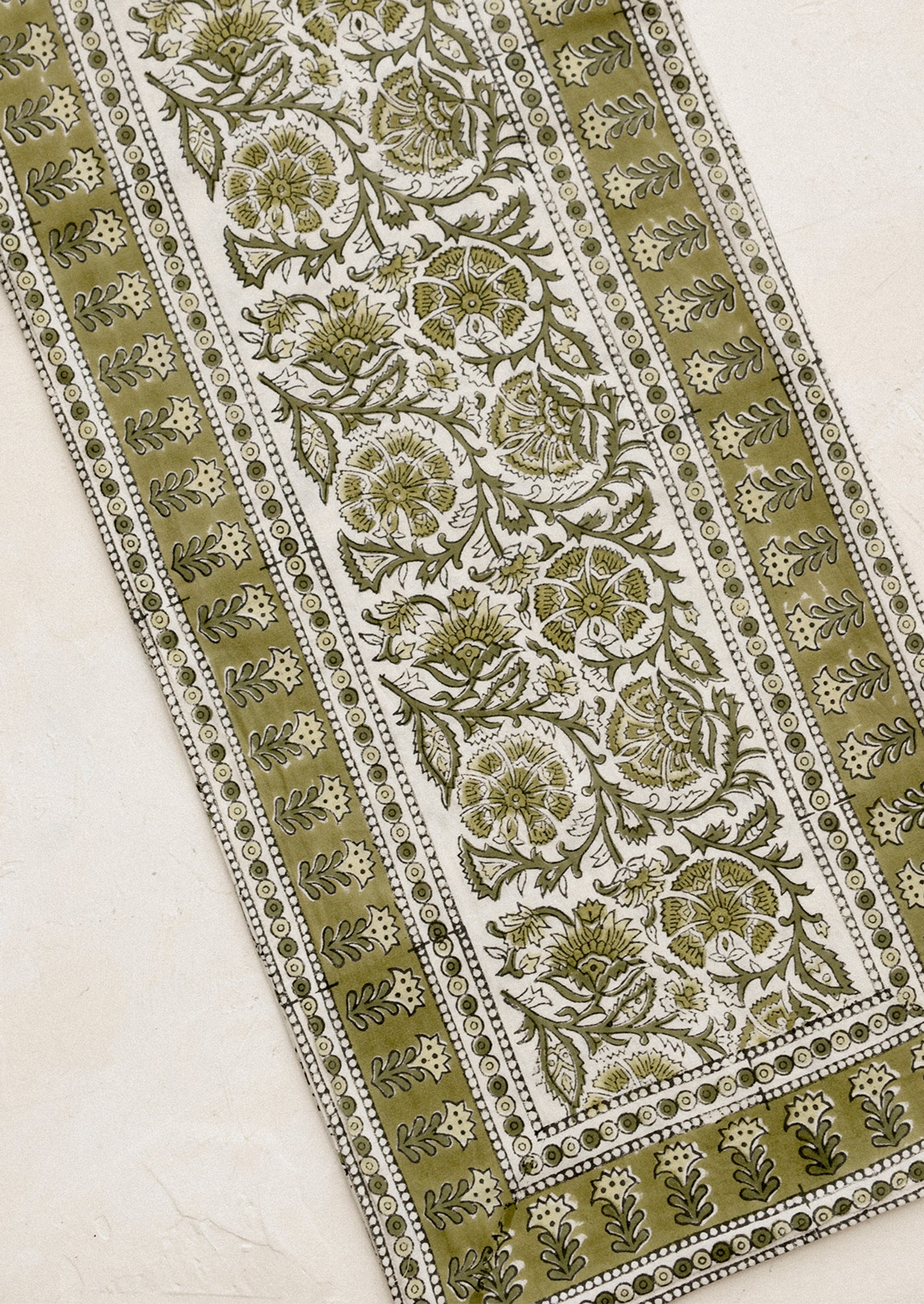 Decorative fabric with intricate green and white floral pattern on a beige background