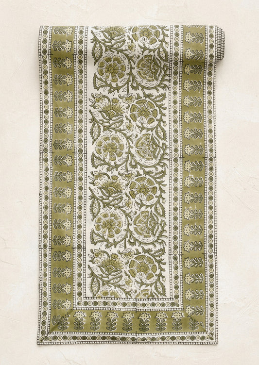 Decorative green and white patterned fabric roll on a beige background