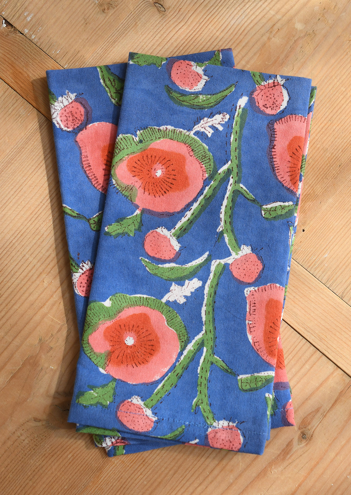 Two blue napkins with floral patterns on a wooden surface