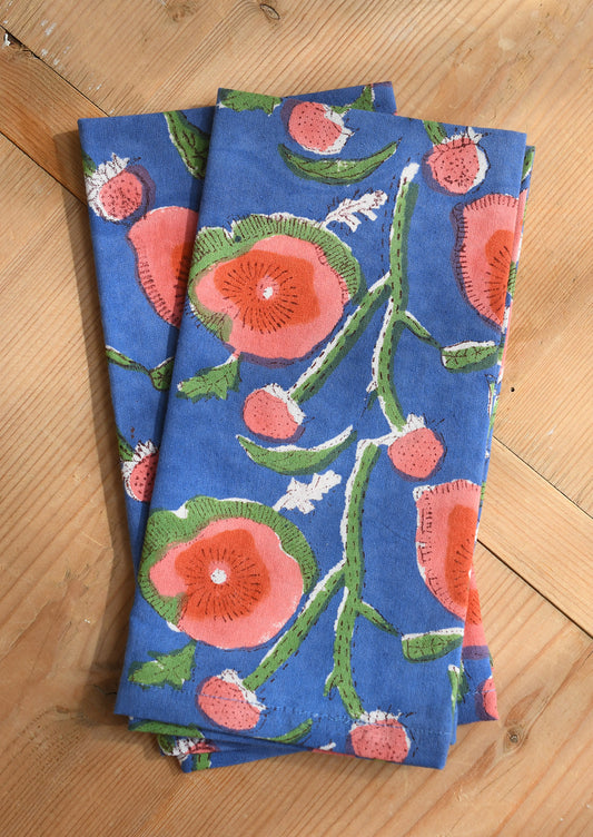 Two blue napkins with floral patterns on a wooden surface