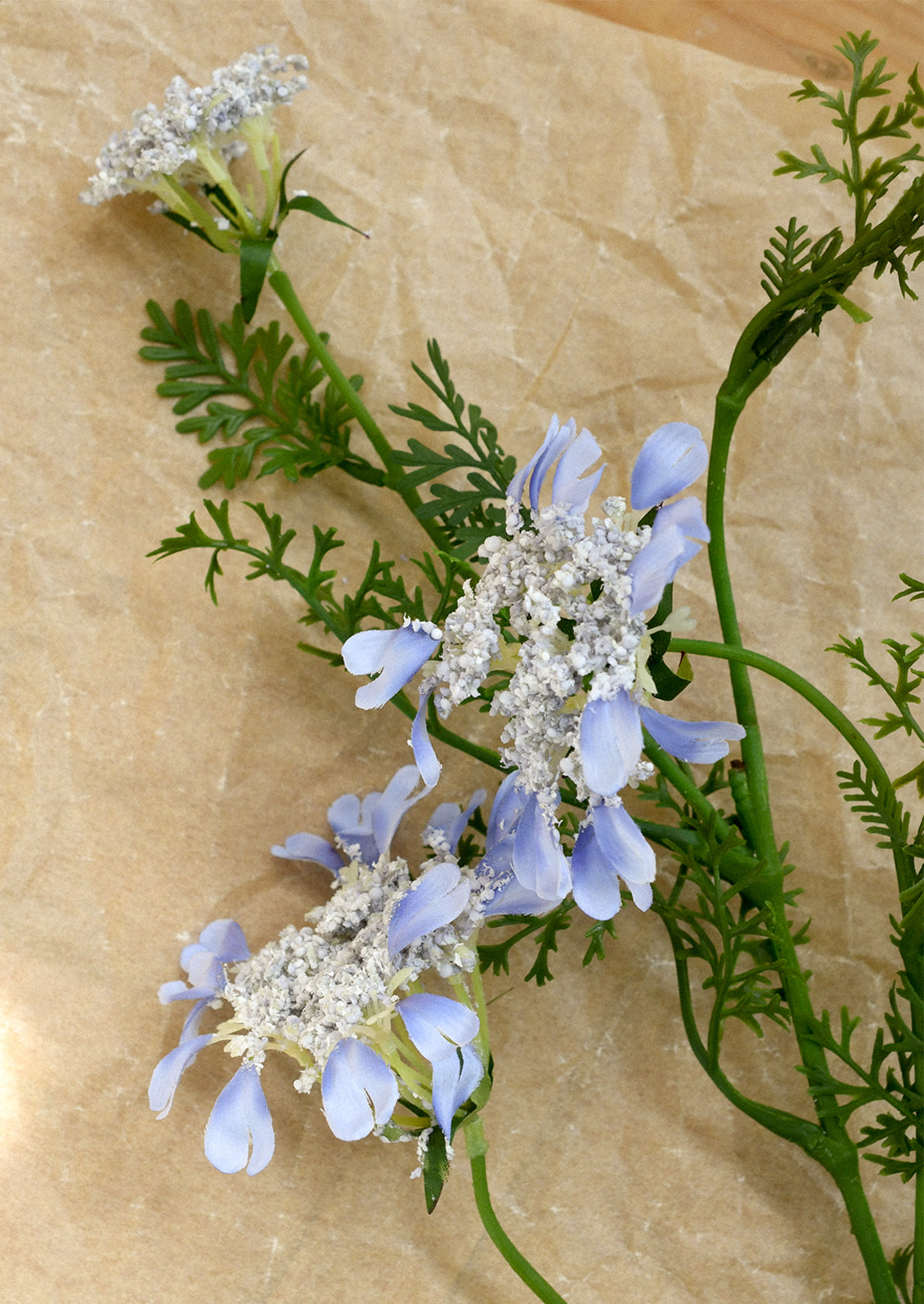Floral arrangement with blue and white flowers on a beige background