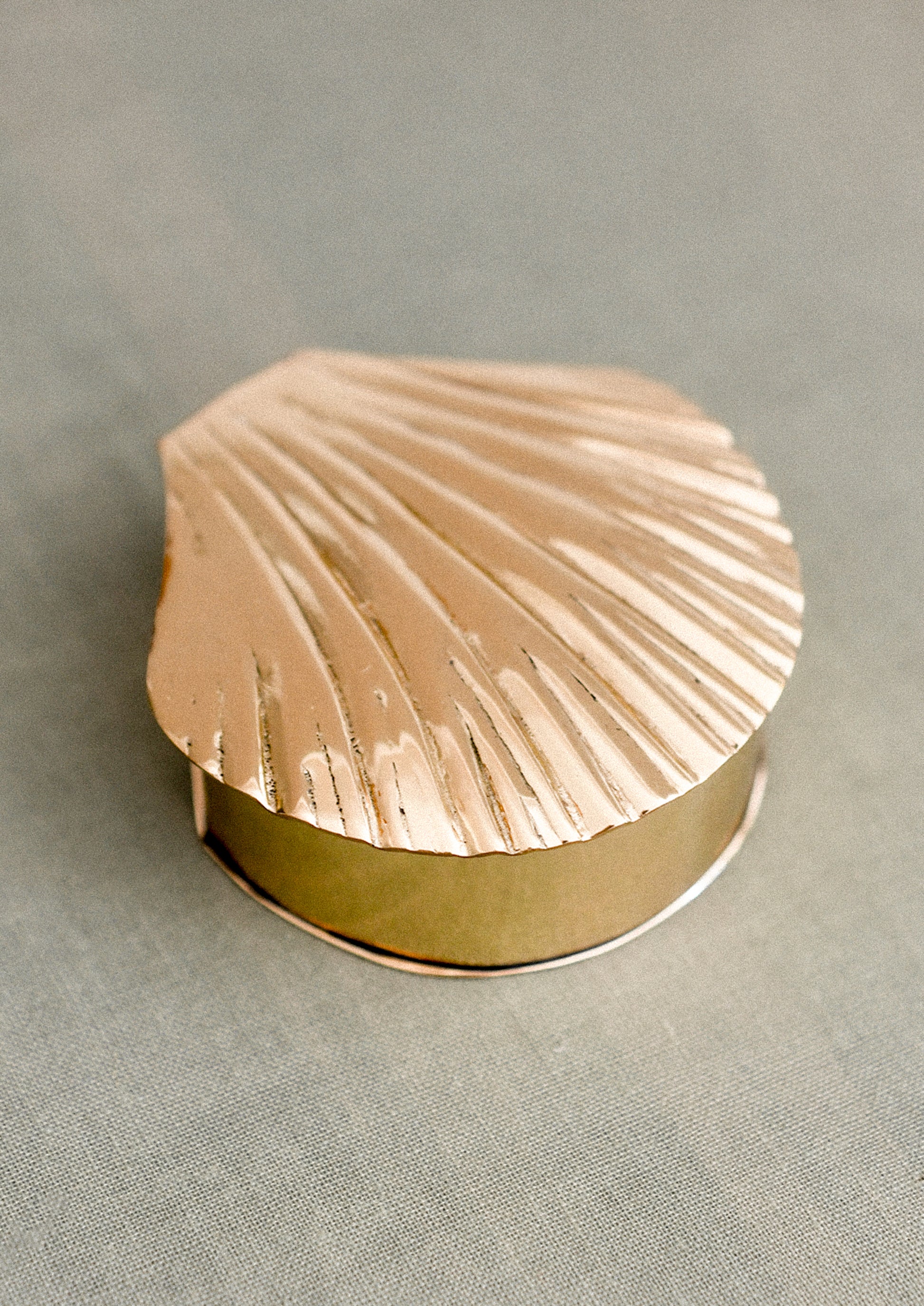 Gold shell-shaped jewelry box on a gray background