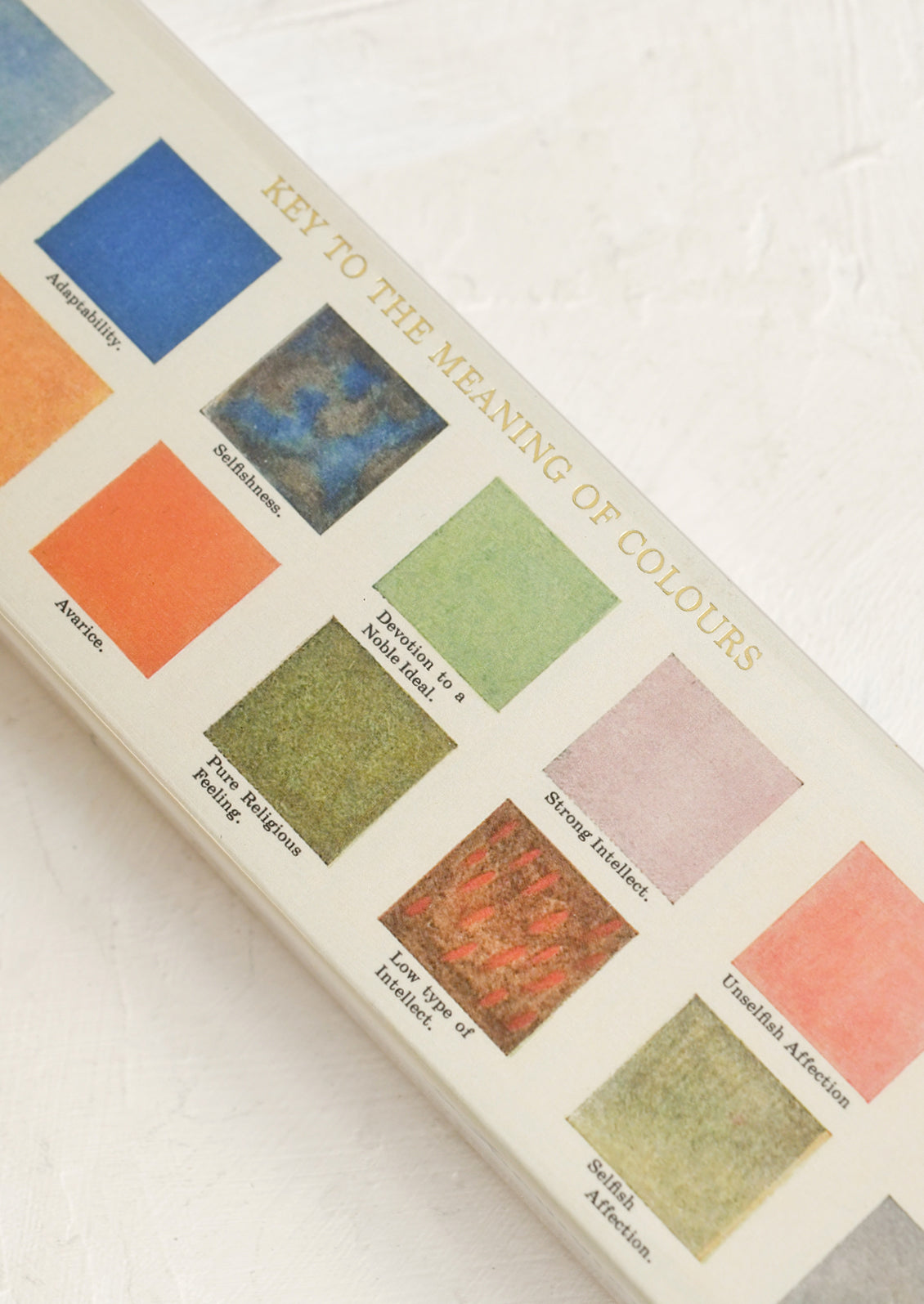 A close-up of a matchbox with 'KEY TO THE MEANING OF COLOURS' text showing labeled color swatches on a white textured background.