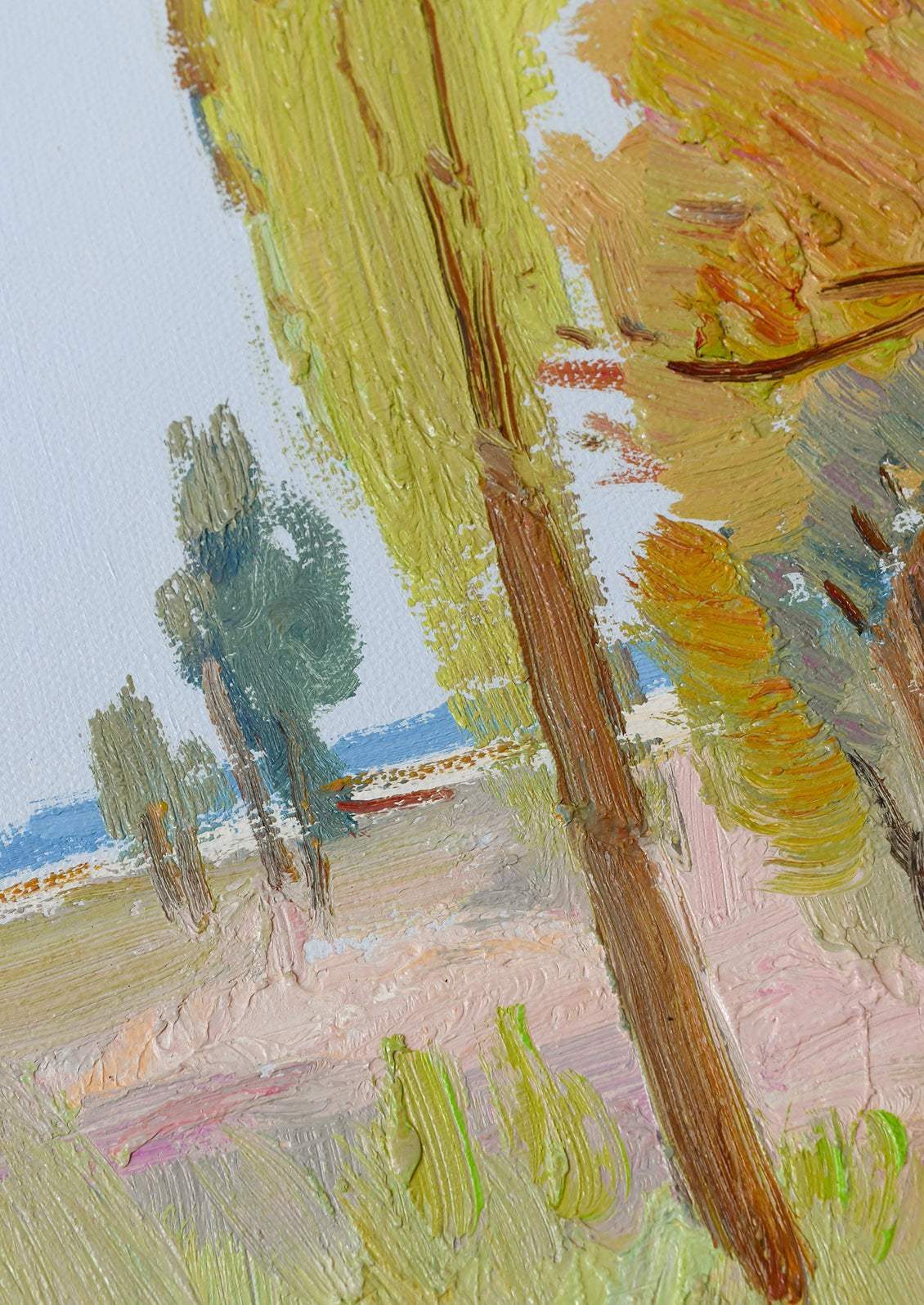 Close-up of an impressionistic landscape painting showing textured brushstrokes of yellow-green trees, a brown trunk, pale pink ground, and a light blue sky.
