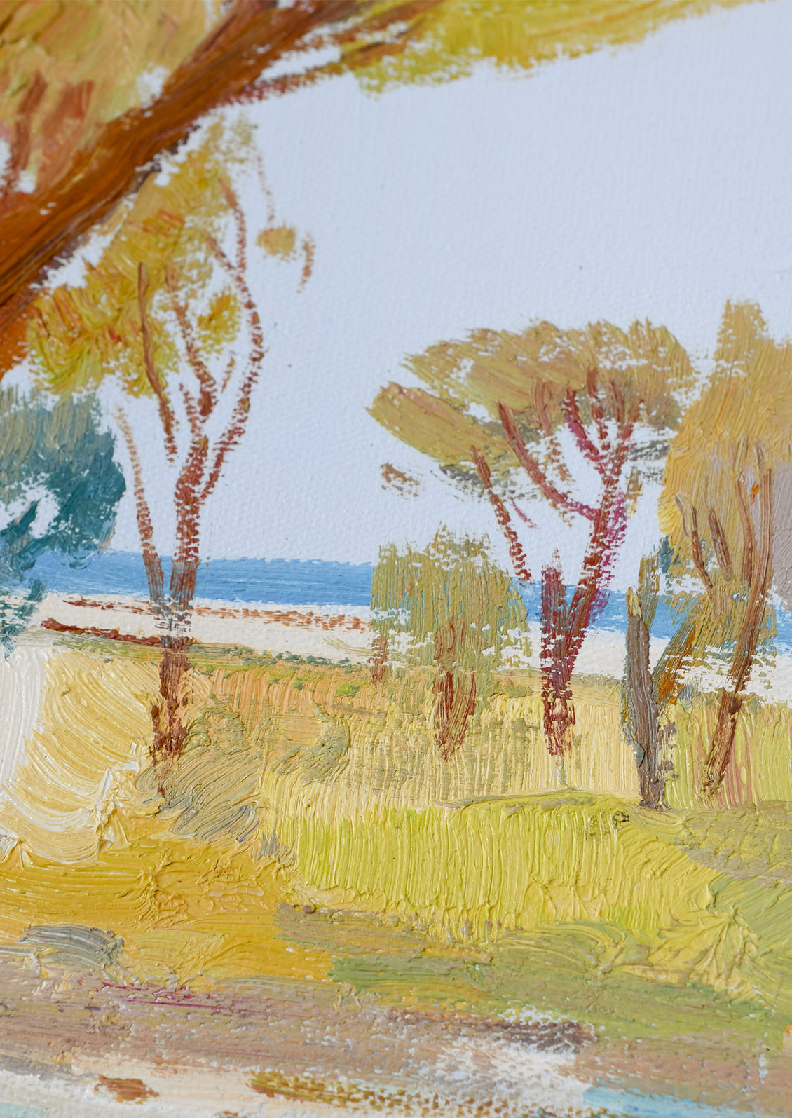 Impressionistic landscape painting featuring trees with yellow and green foliage, a blue sea in the distance, and a pale sky, rendered with visible brushstrokes.