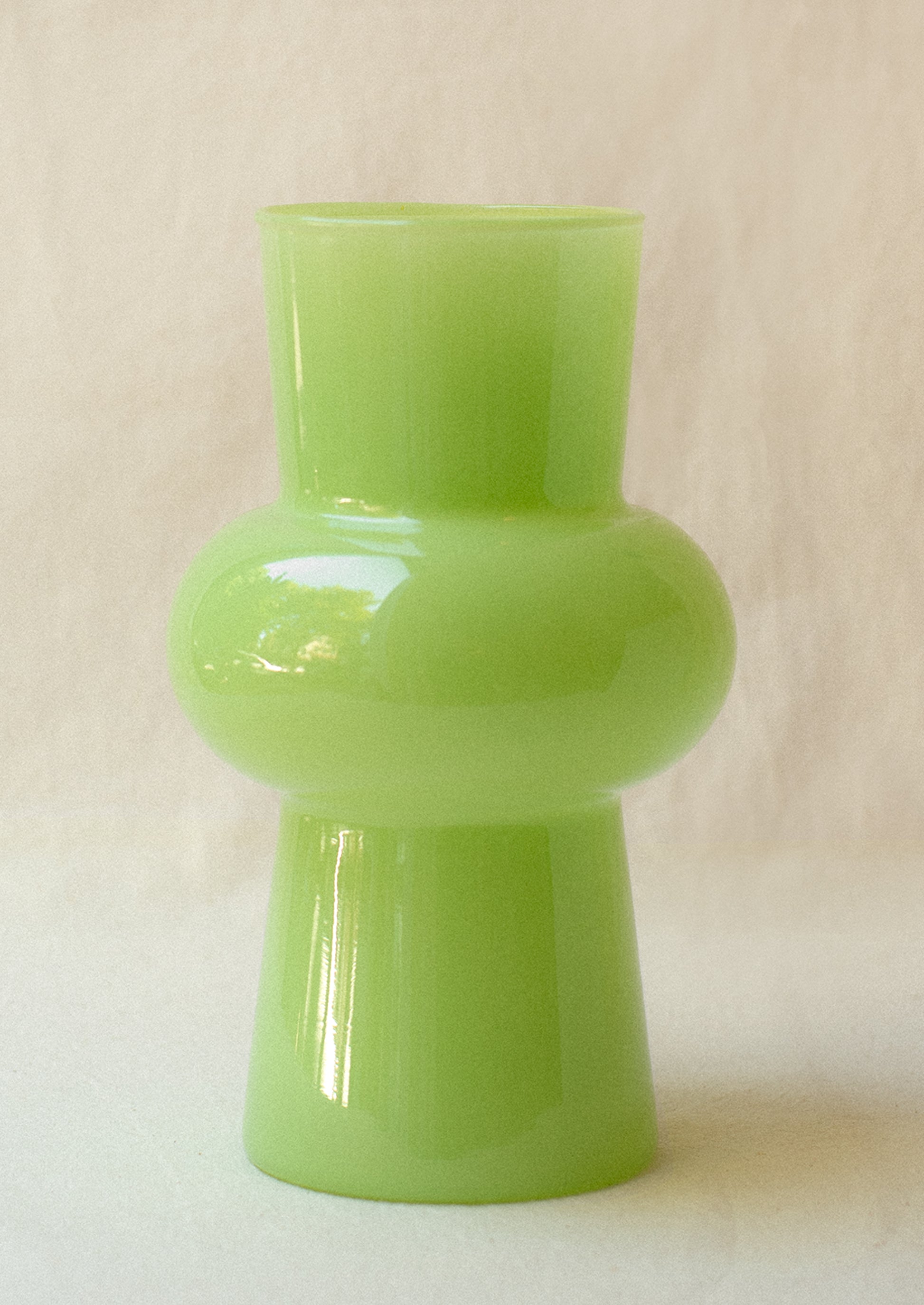 A glass vase with bulbous middle in translucent melon green hue.