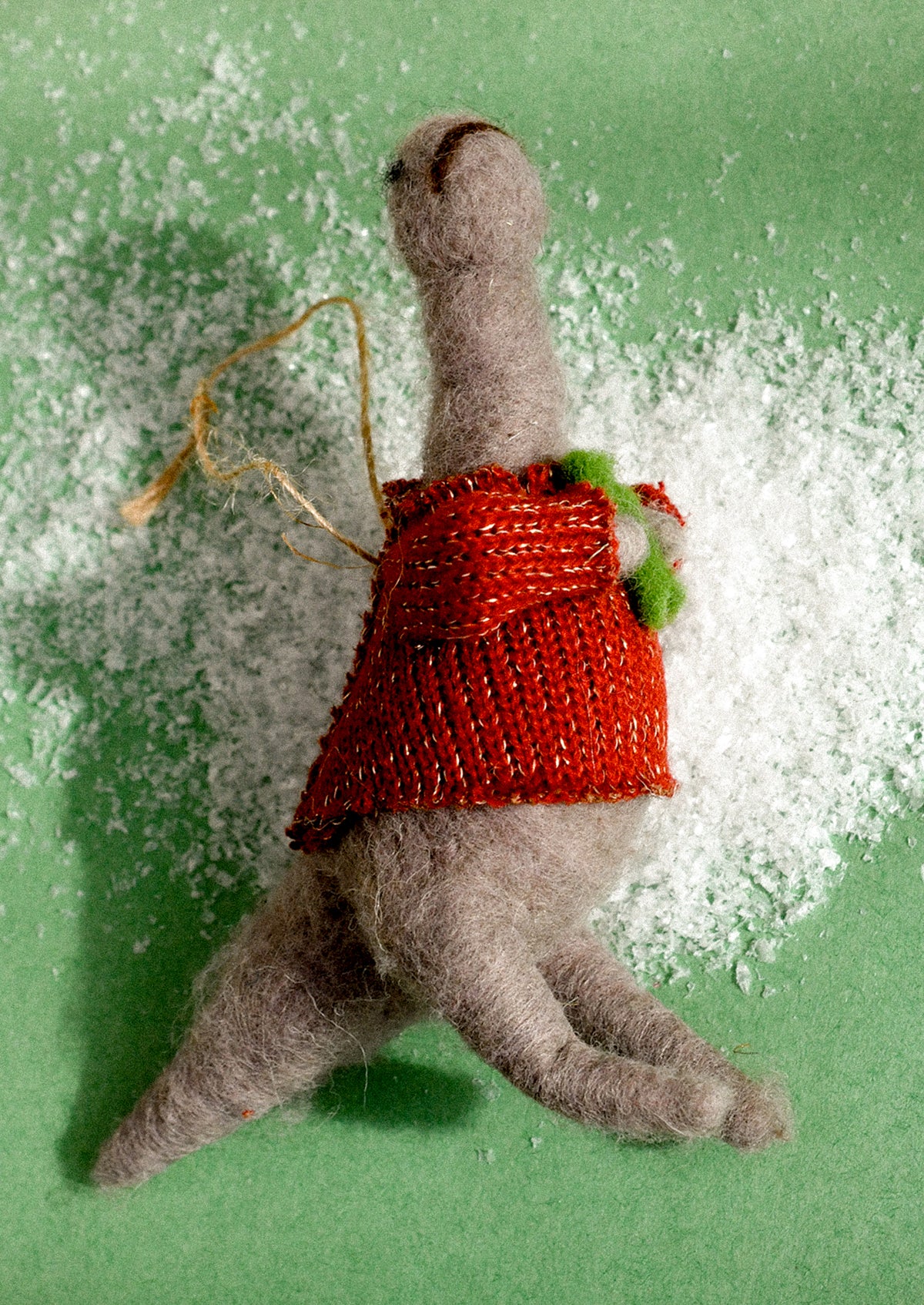 A felted wool ornament of a dinosaur wearing a sweater.