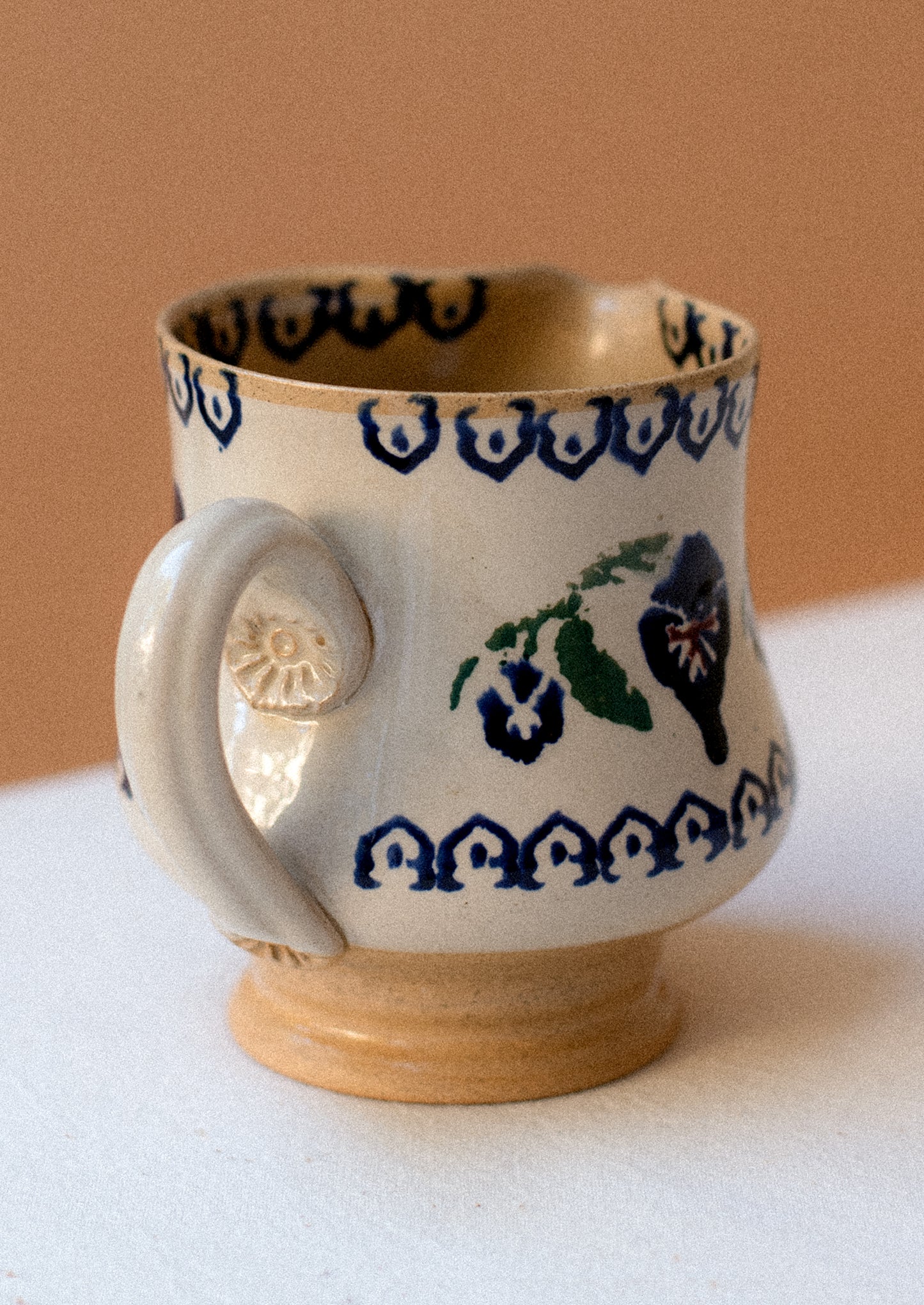 A ceramic pitcher with hand painted pansy floral pattern.