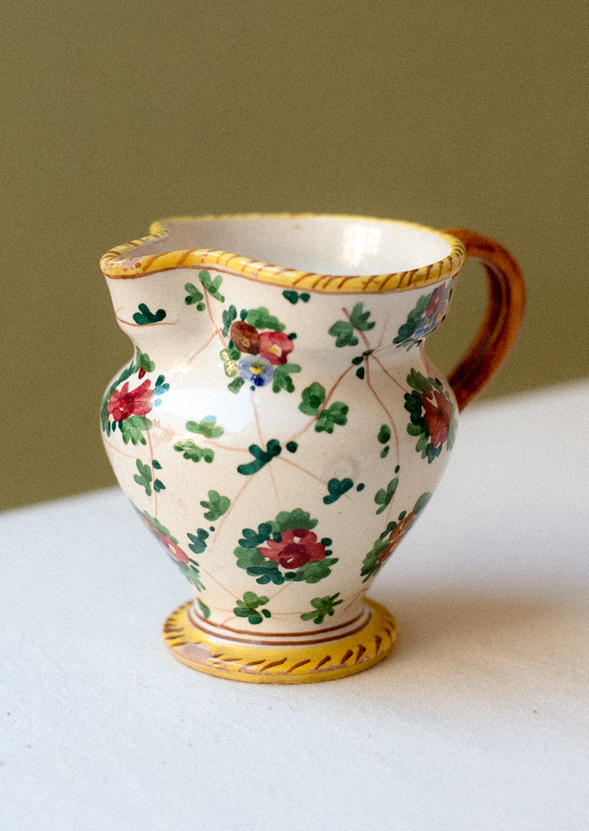 A painted porcelain pitcher with floral pattern.