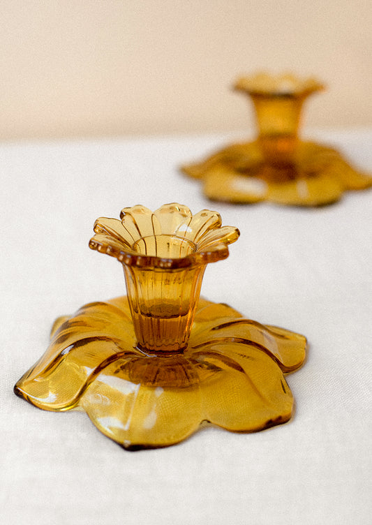 A pair of amber glass candle holders in the shape of daffodils.