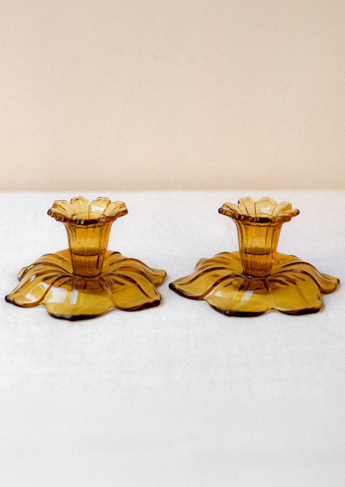 A pair of amber glass candle holders in the shape of daffodils.
