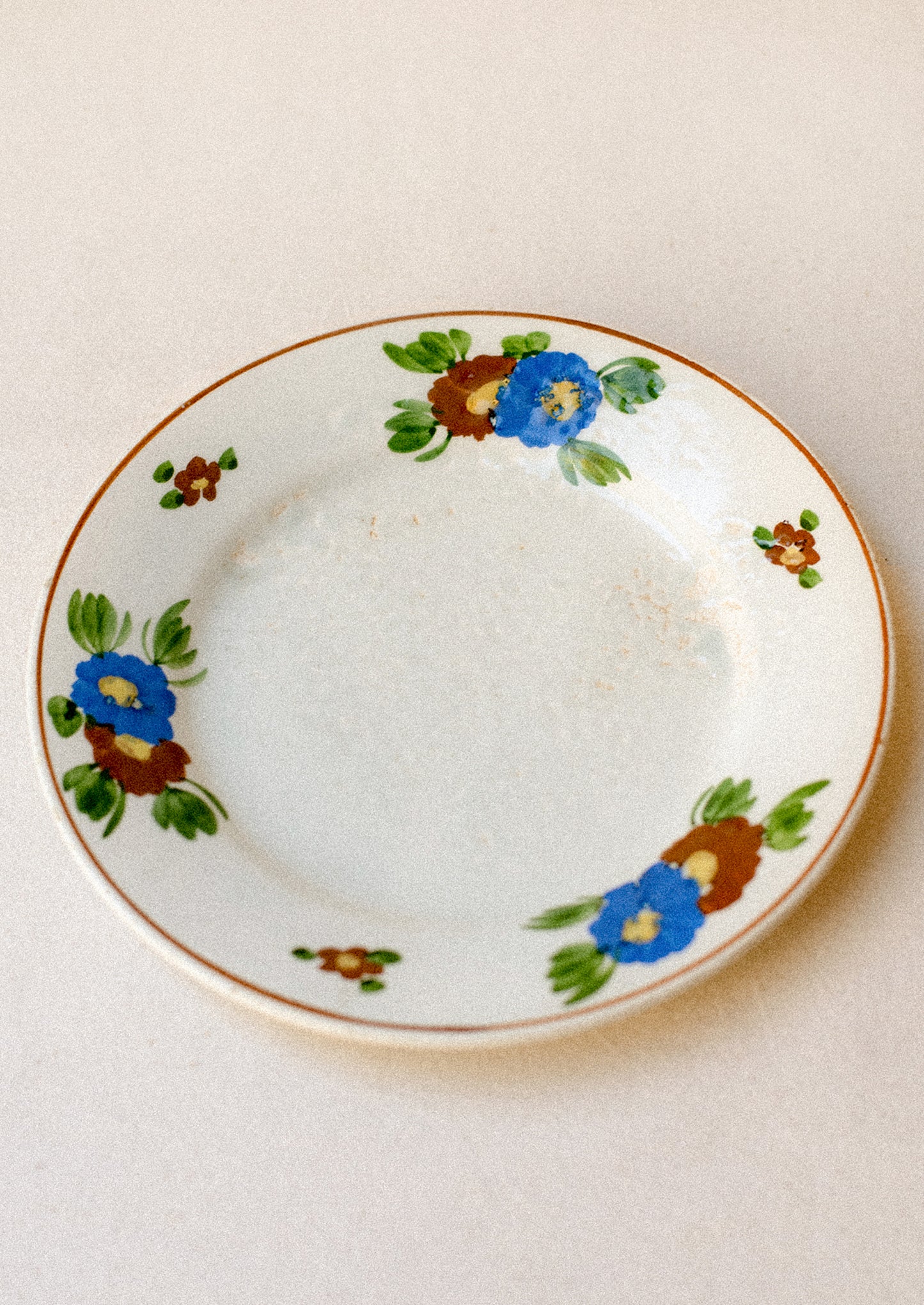 A ceramic plate with blue and brown painted floral pattern.