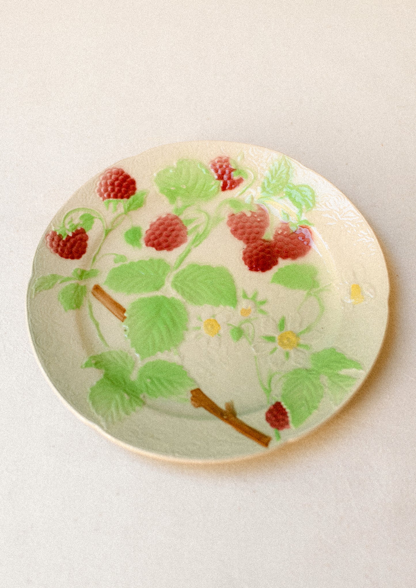 A ceramic plate in ivory with hand painted raspberry motif.