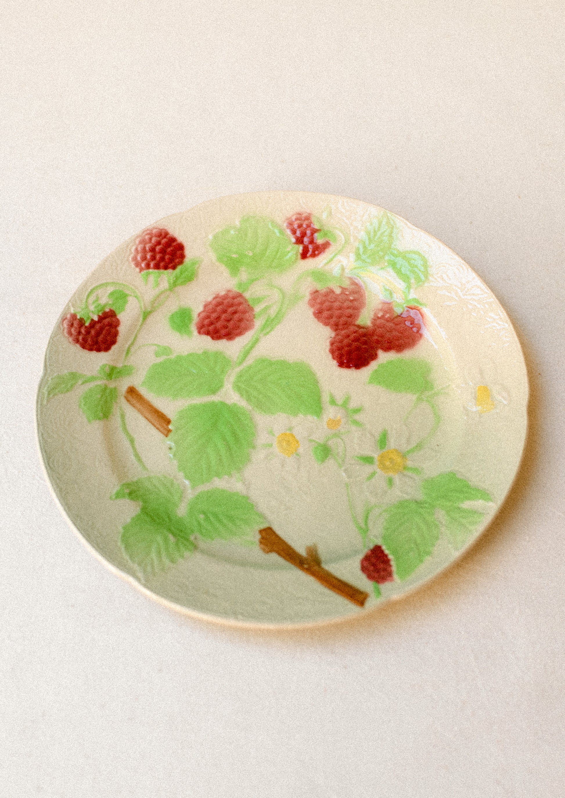 A ceramic plate in ivory with hand painted raspberry motif.