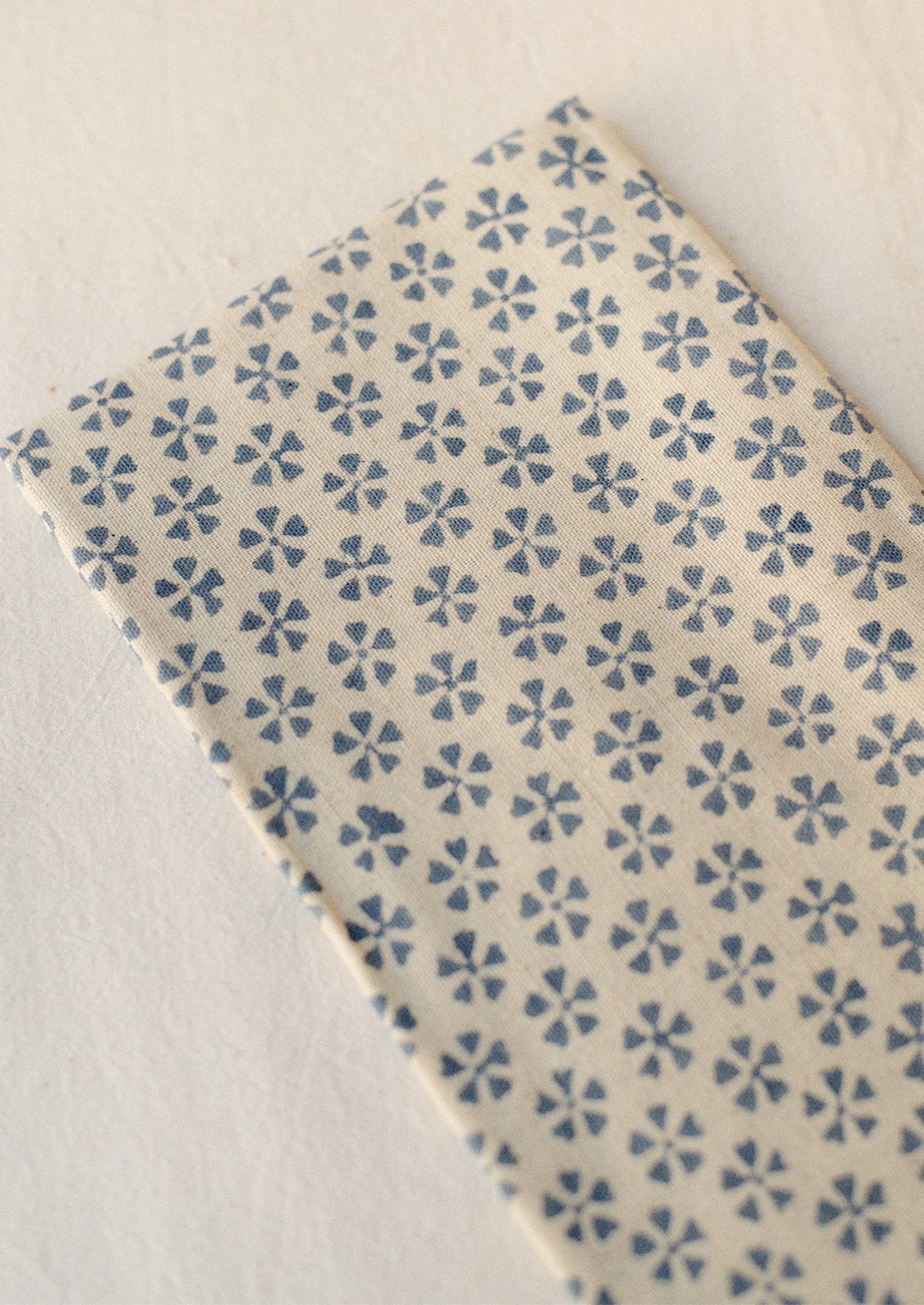 A pair of natural cotton-linen napkins with blue repeating floral pattern.