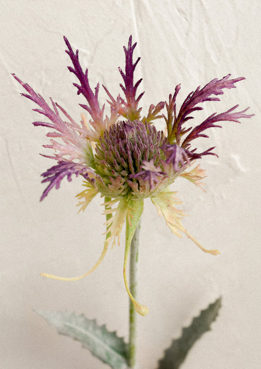 A faux flower stem depicting a purple thistle flower.