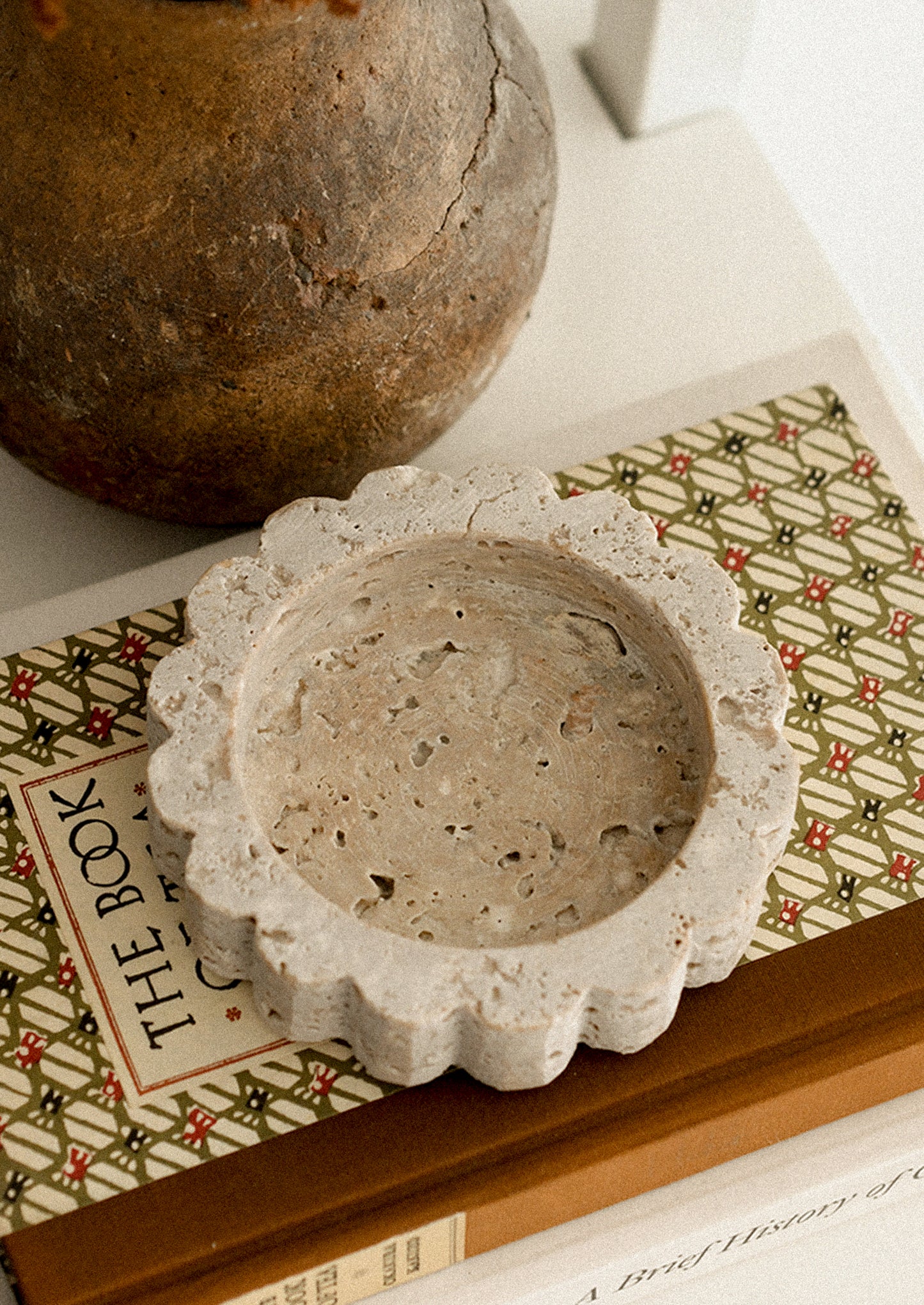 A small round travertine tray with scalloped edges.