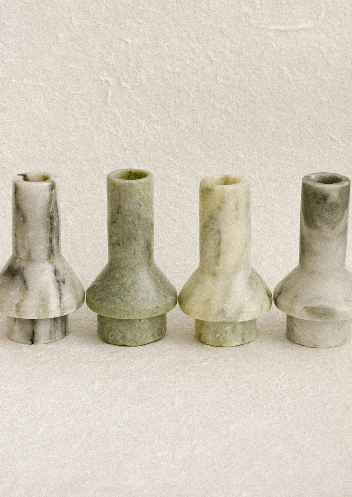 Sculptural candle holders in variegated green marble.