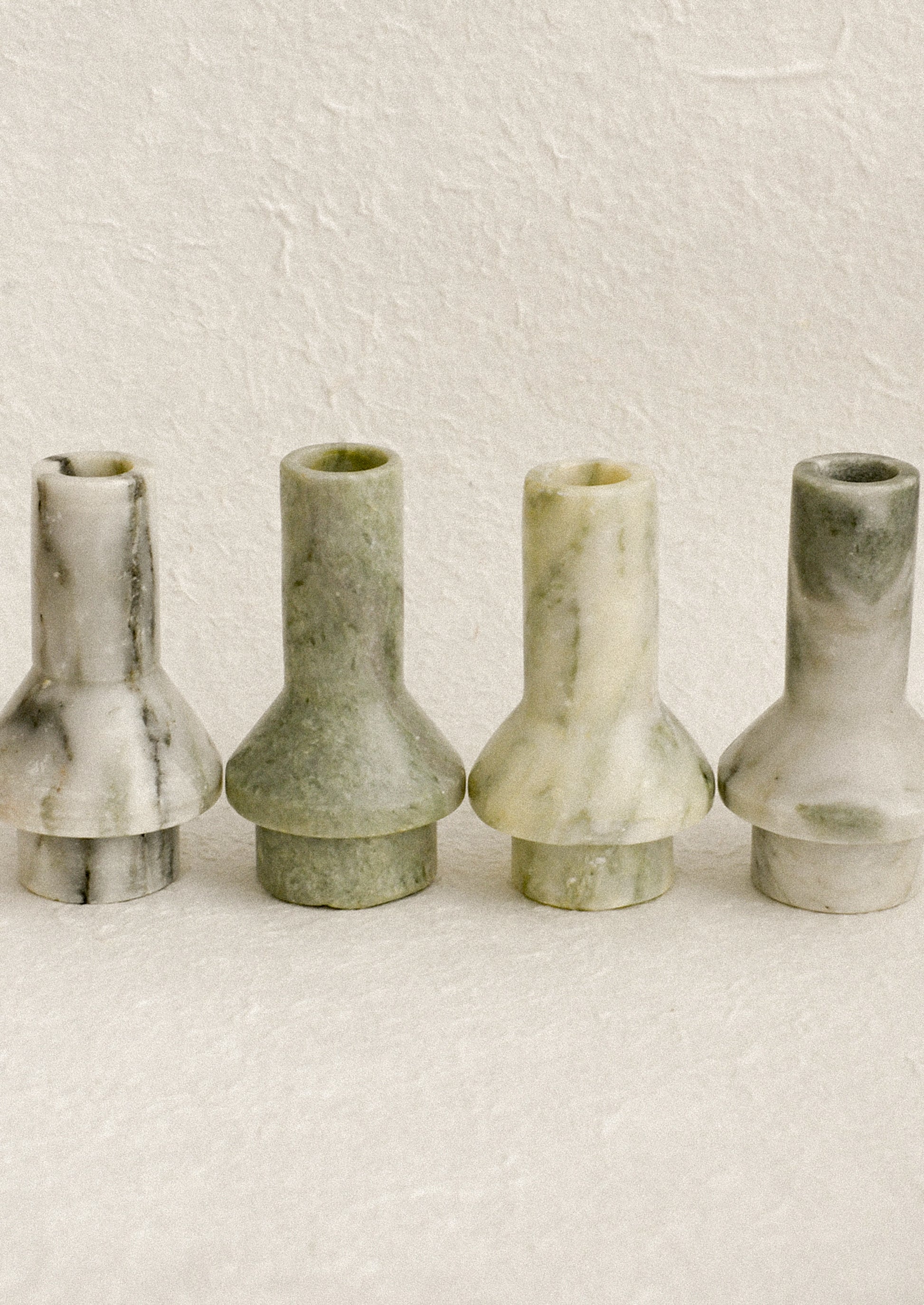 Sculptural candle holders in variegated green marble.