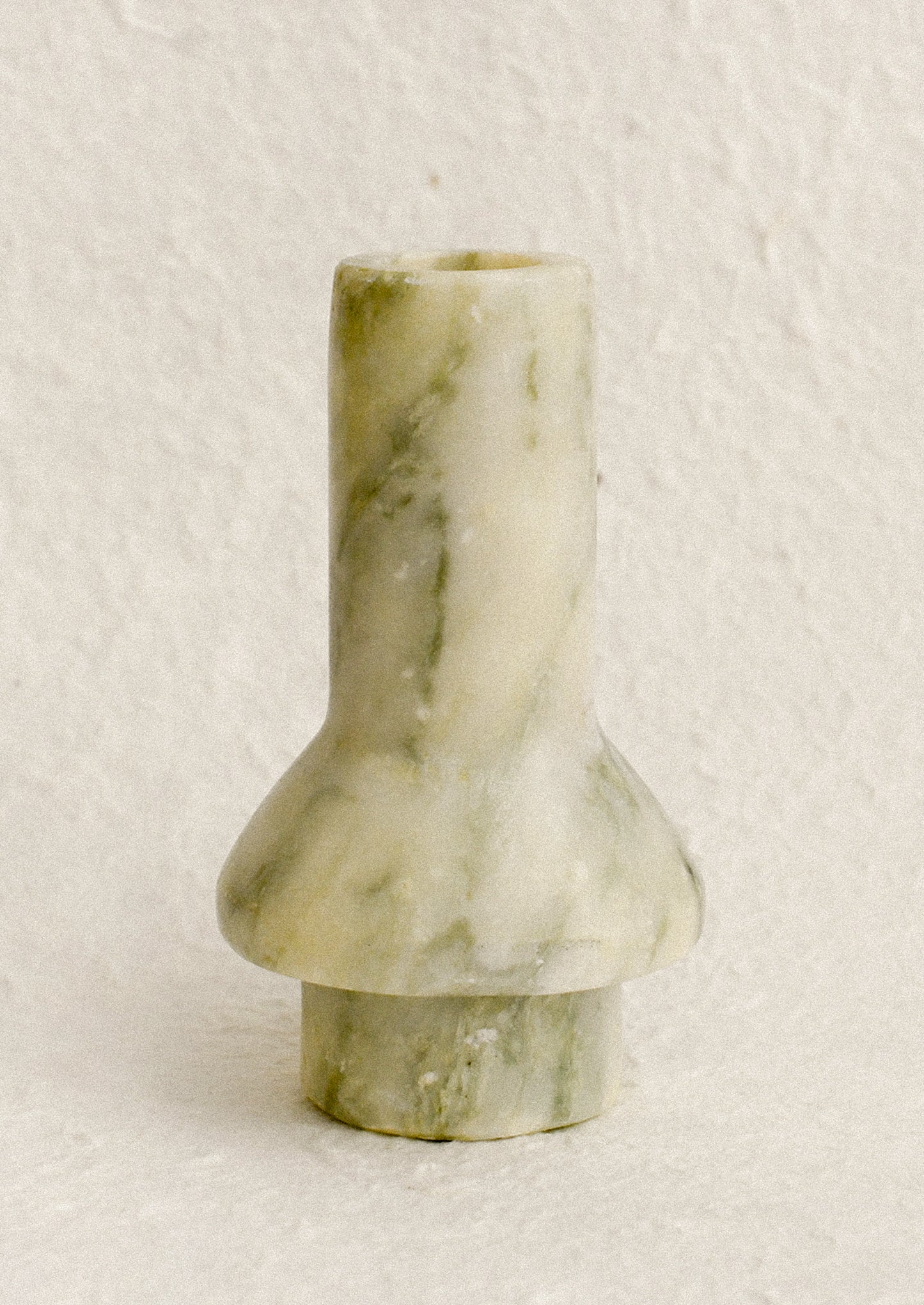 A sculptural candle holder in variegated green marble.