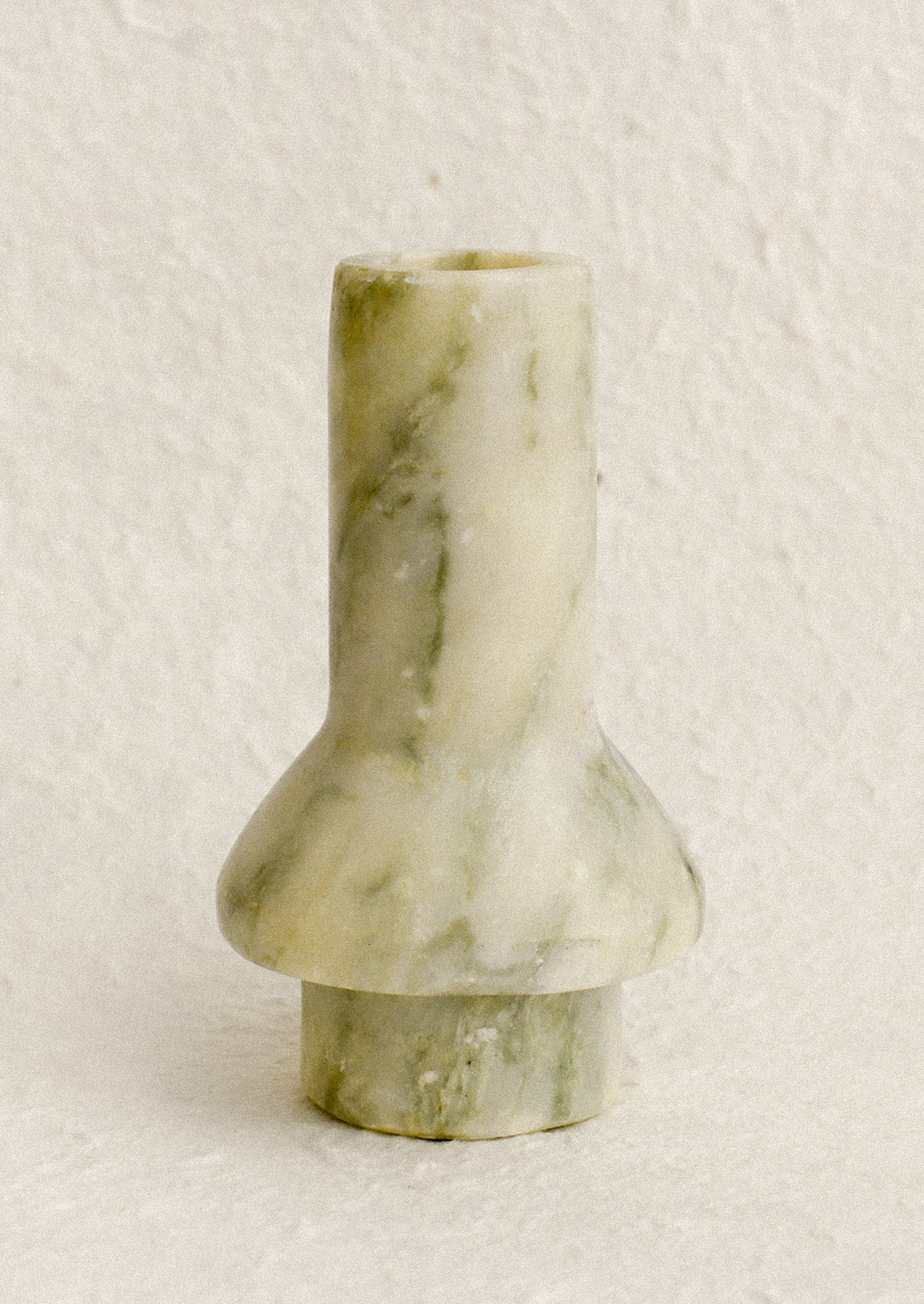 A sculptural candle holder in variegated green marble.
