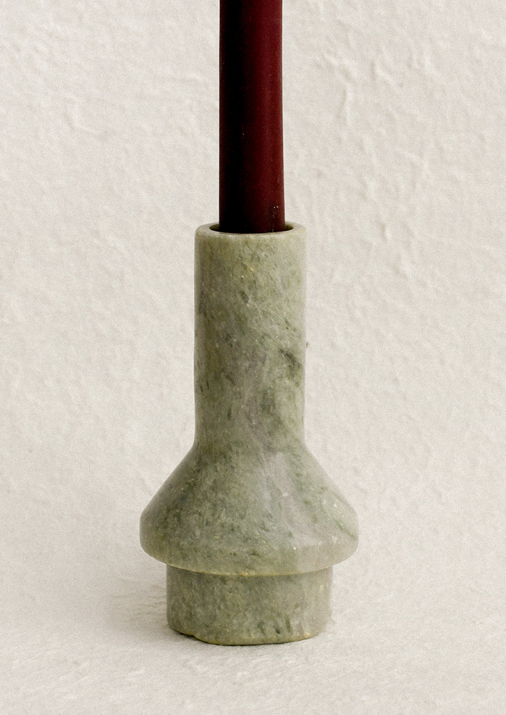A sculptural candle holder in variegated green marble.