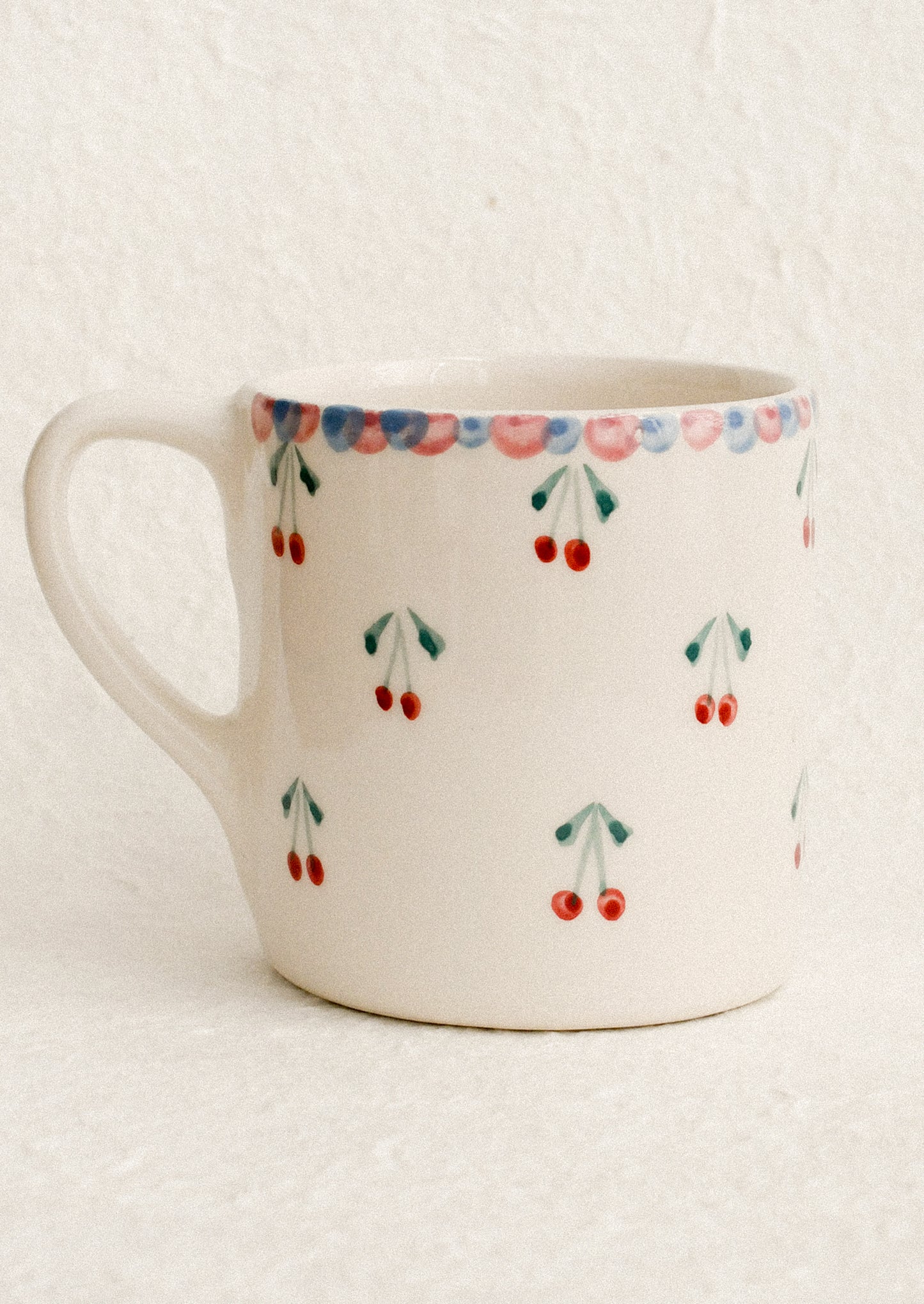 A hand painted mug with cherries motif.