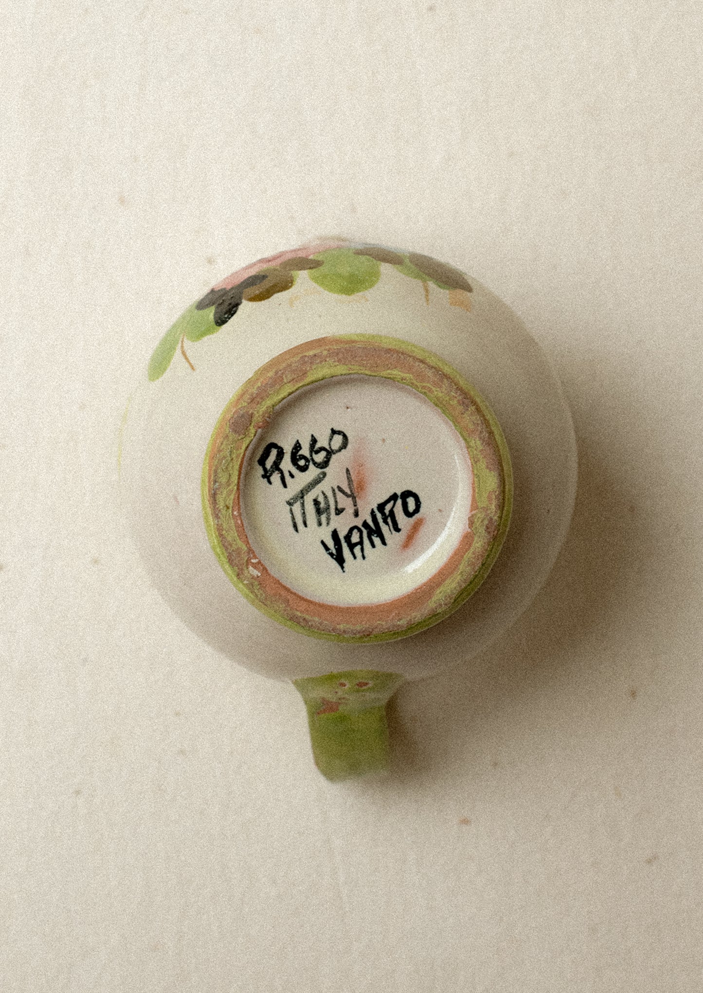 A small ceramic pitcher with painted floral design and green border.