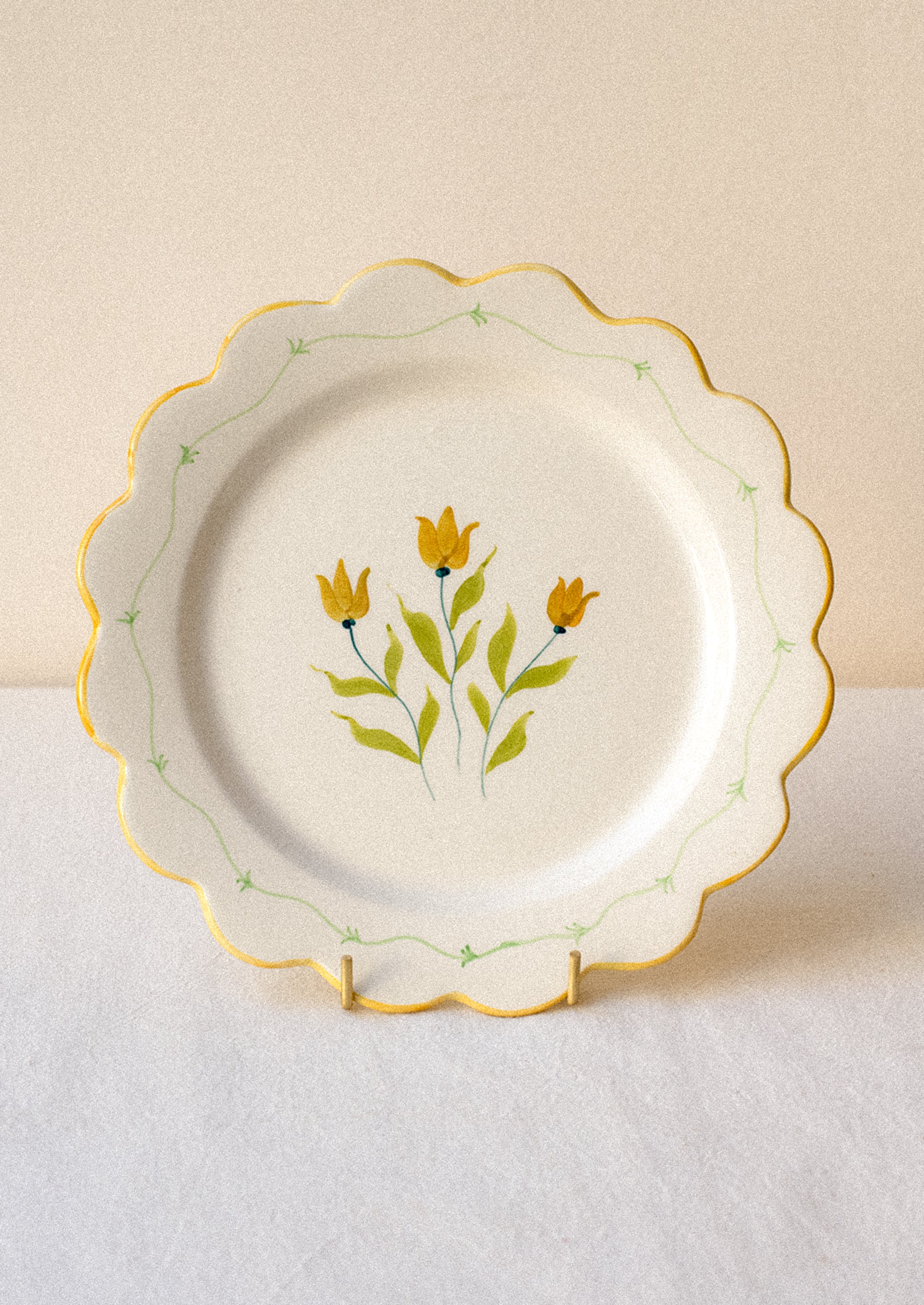 Decorative ceramic plate with yellow floral design and yellow scalloped edge.