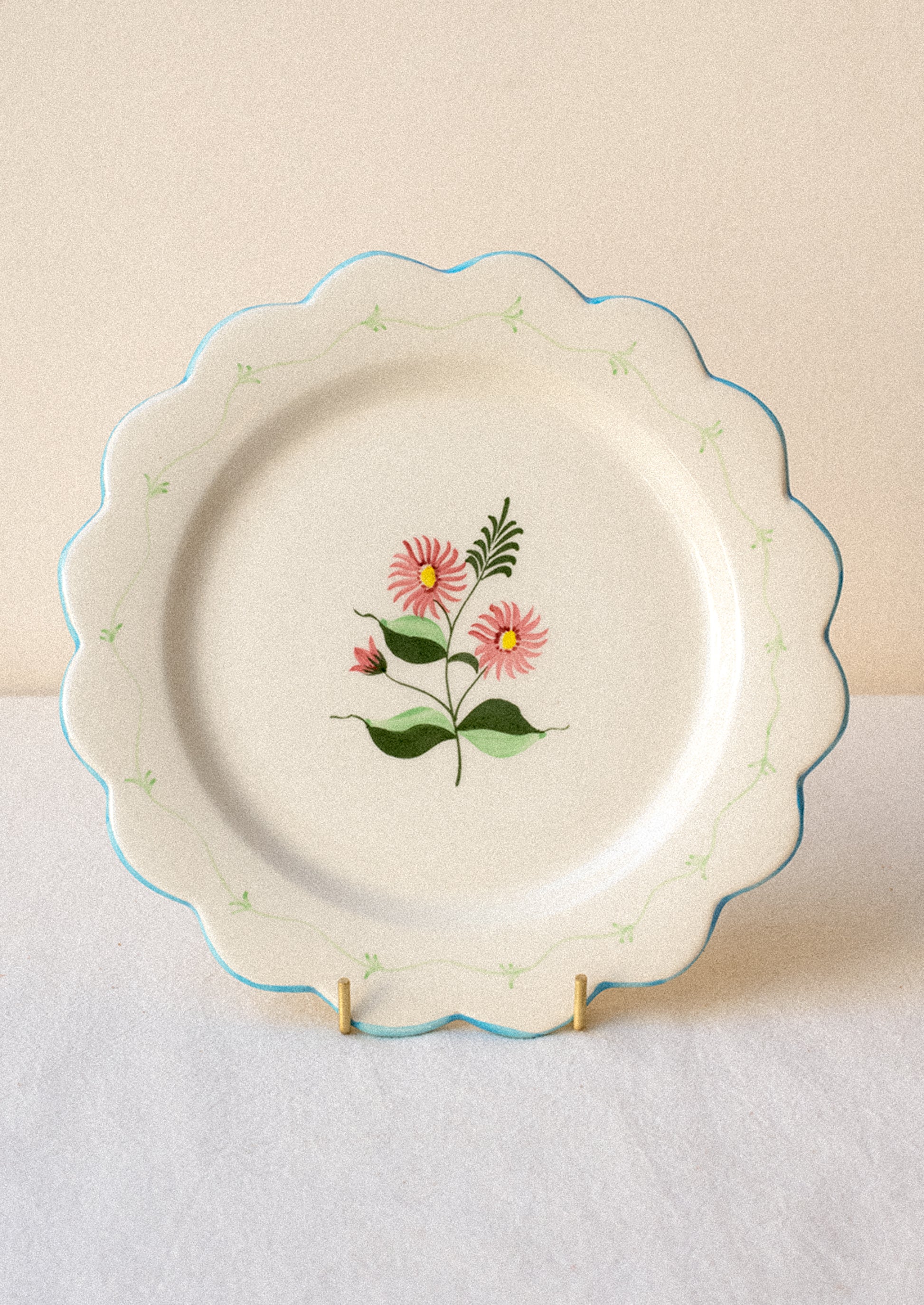 Decorative ceramic plate with pink floral design and blue scalloped edge.
