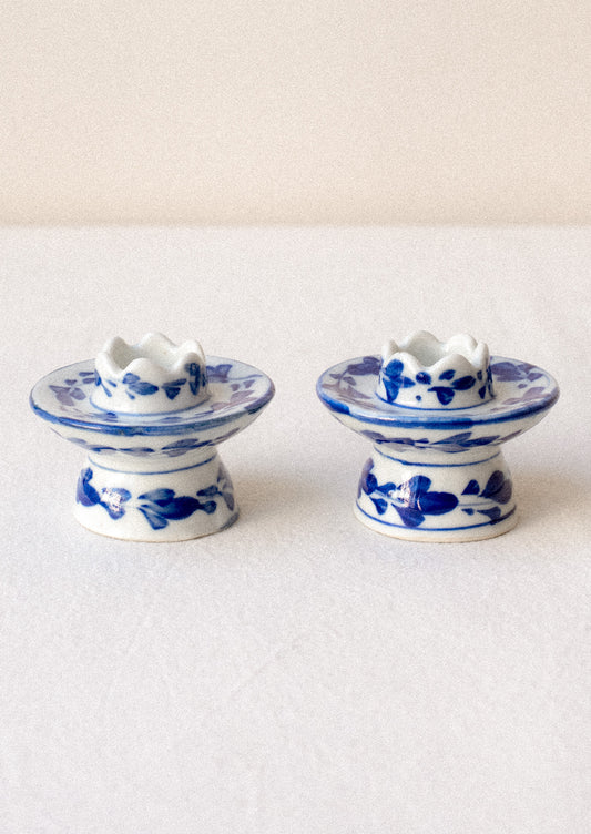 A pair of small blue and white floral print ceramic candleholders.