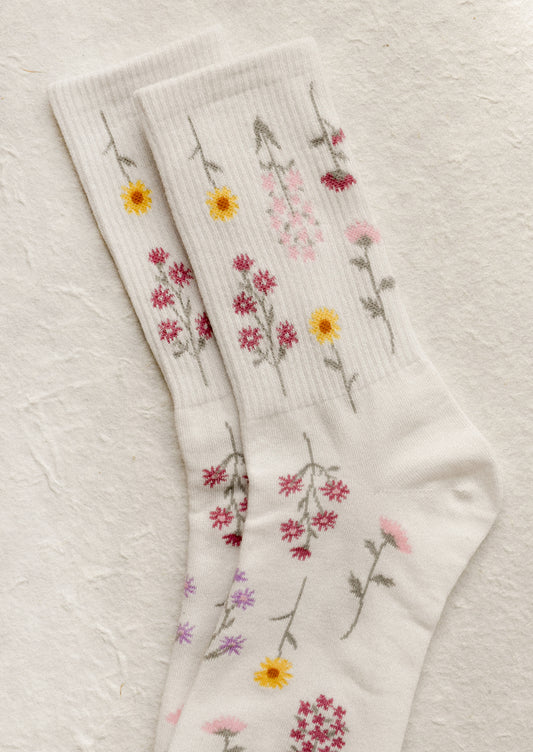 A pair of white socks with pink and yellow flower pattern.