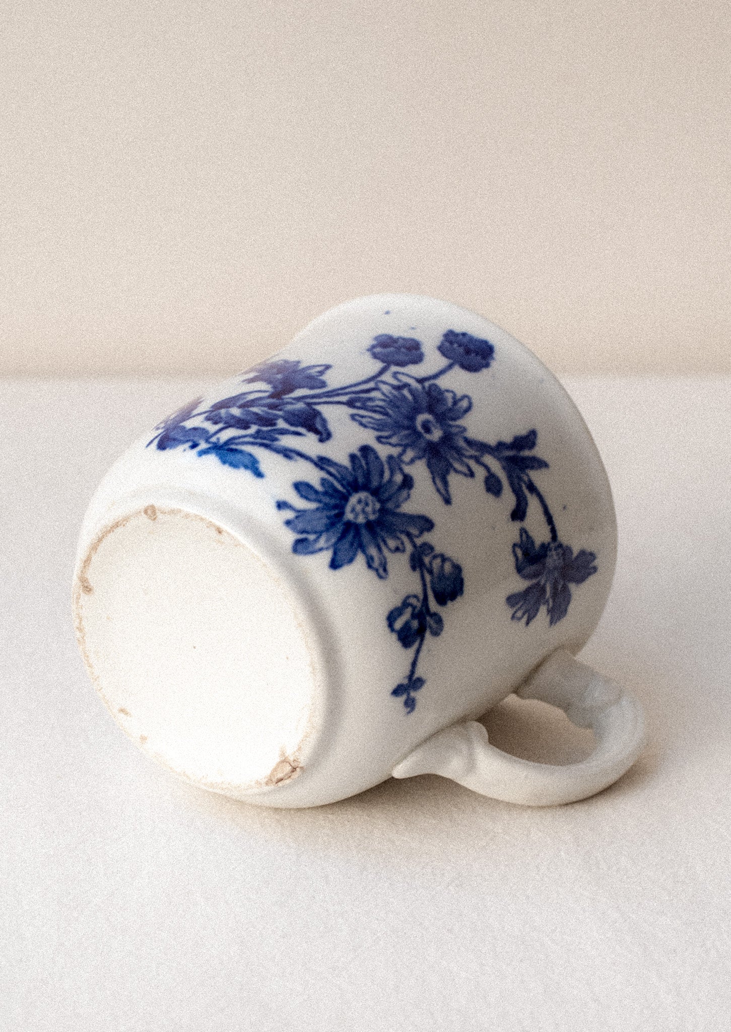 A white mug with flow blue floral pattern and ornate handle.